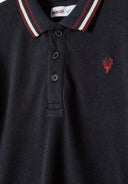 Detail of a boys' long sleeve polo with a woven collar and button placket.
