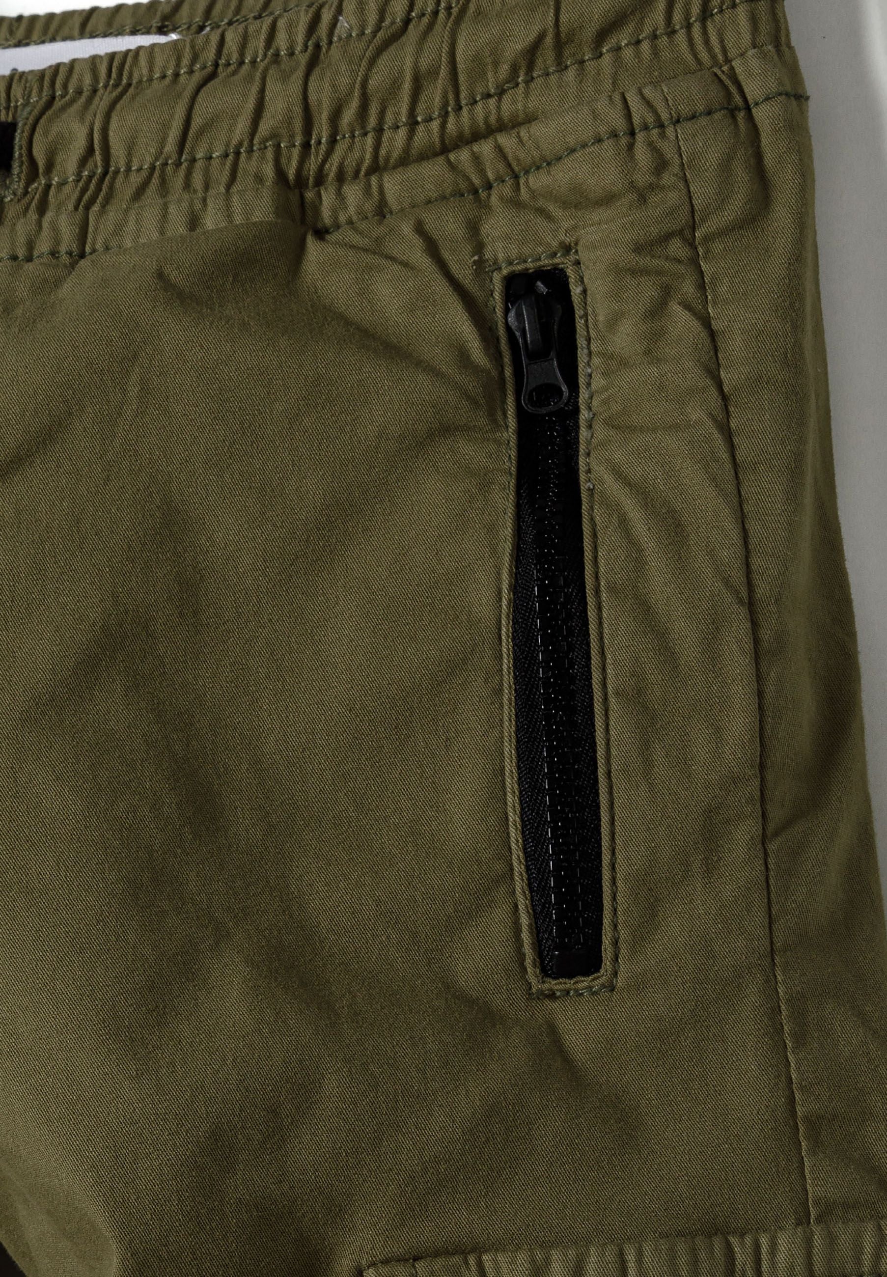 Detail of boys cargo trousers in olive green with zip pocket.