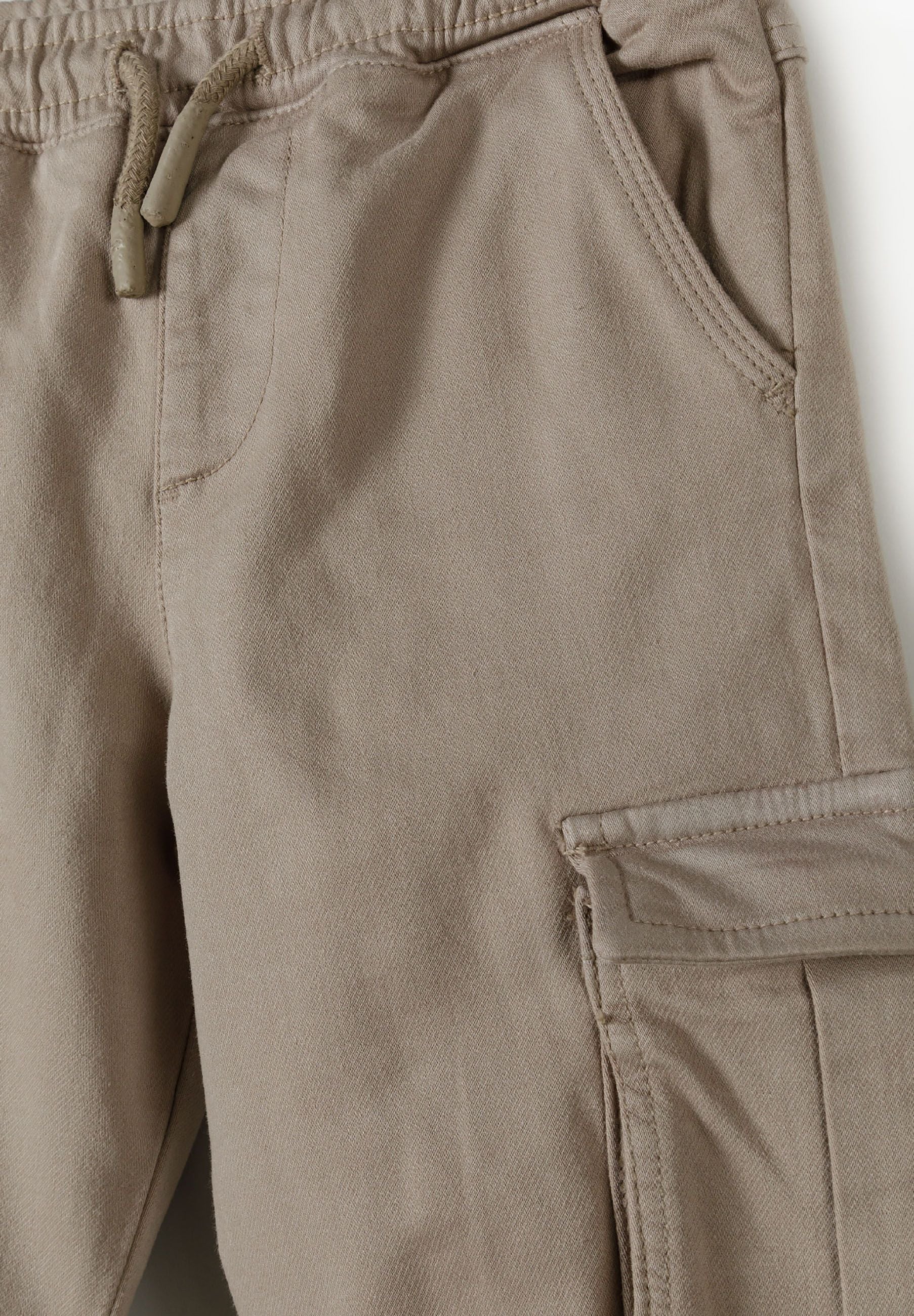 Detail of boys' cargo trousers with elasticated waistband and side pocket.