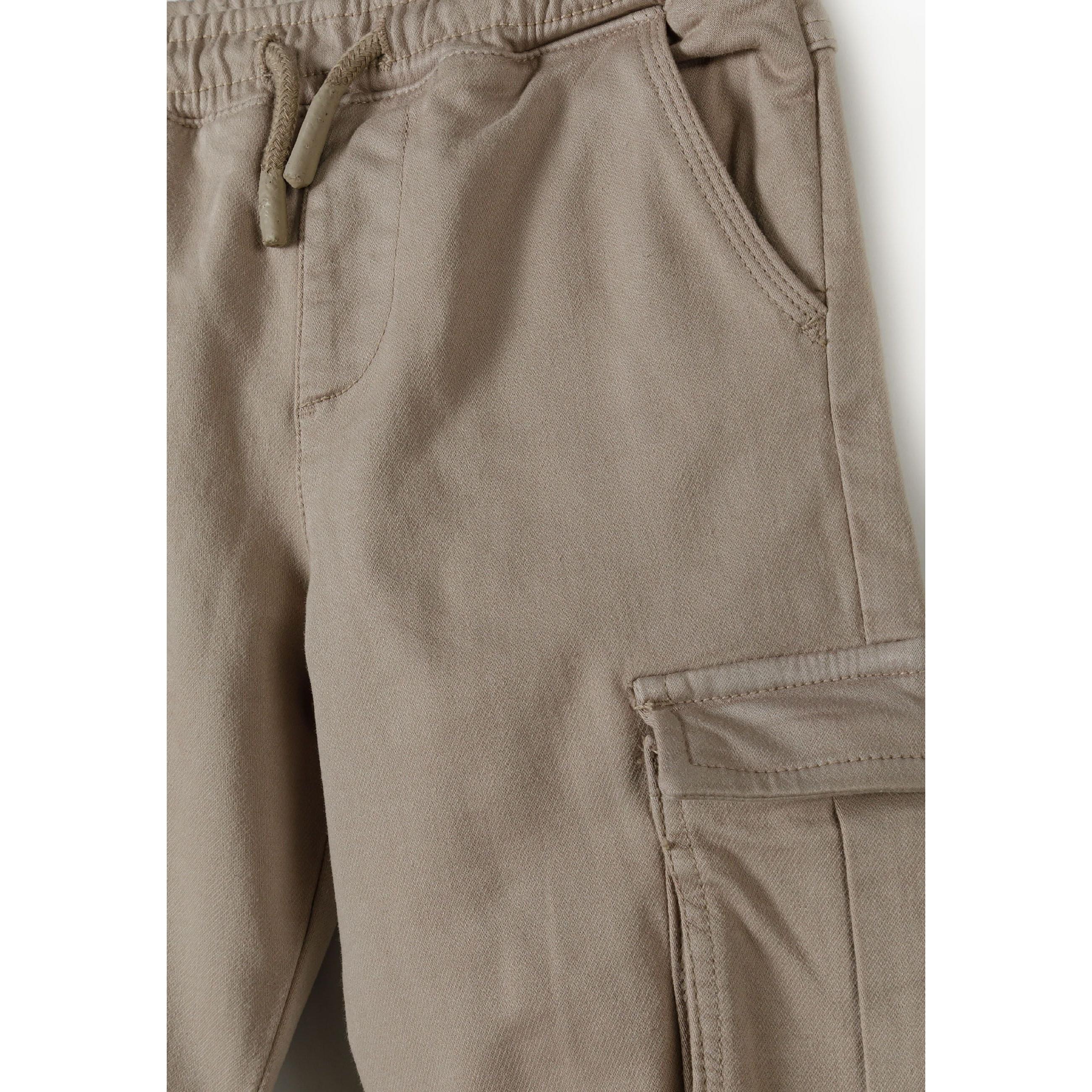 Close-up detail of grey cargo trousers showing elasticated waistband with drawstring ties and cargo pocket construction
