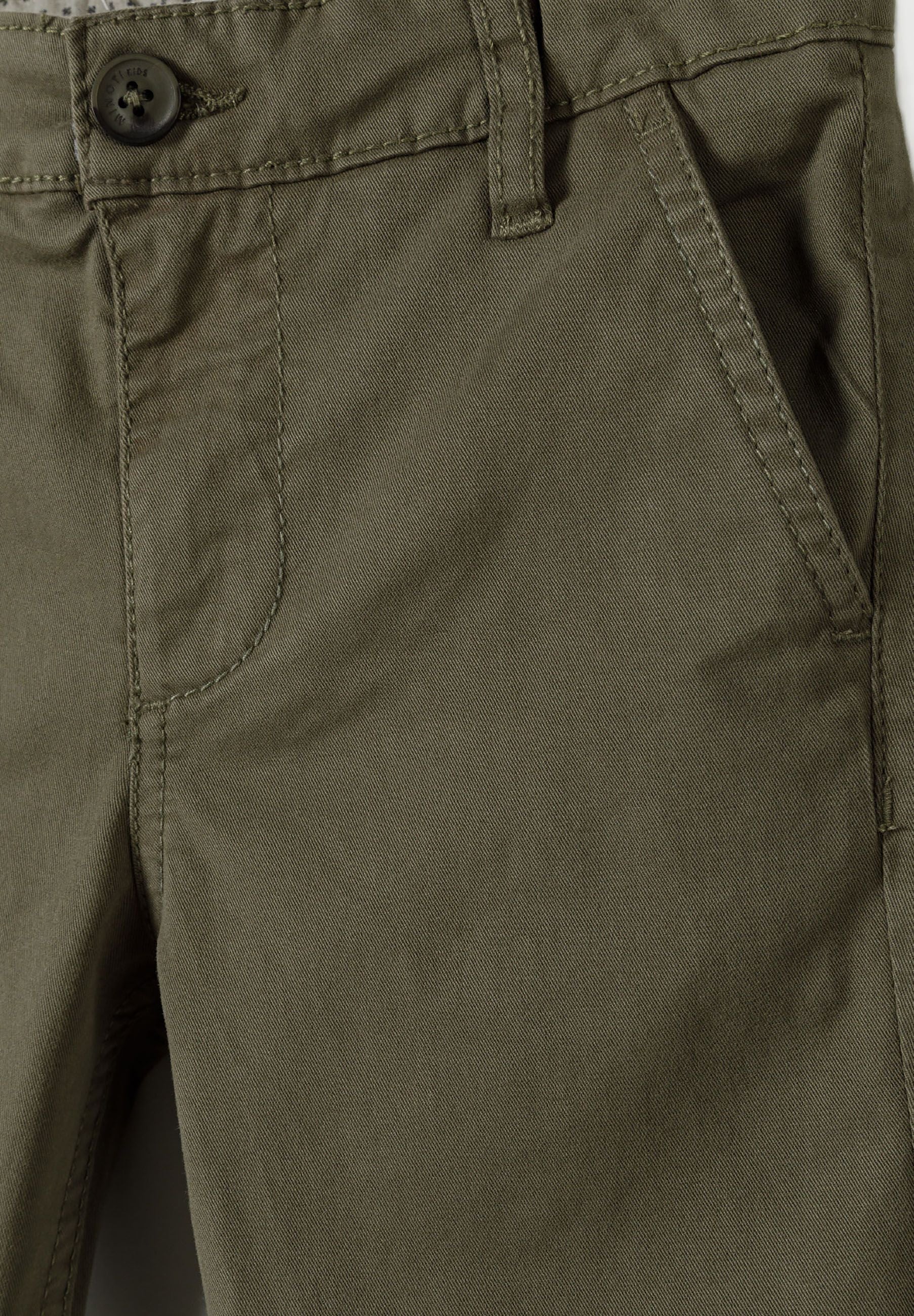 Detail of boys' khaki chino trousers featuring a front pocket and button closure.