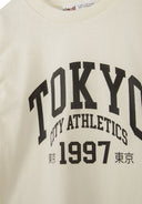 Tokyo City Athletics sweatshirt featuring bold black print and soft cream fabric for casual comfort and style.