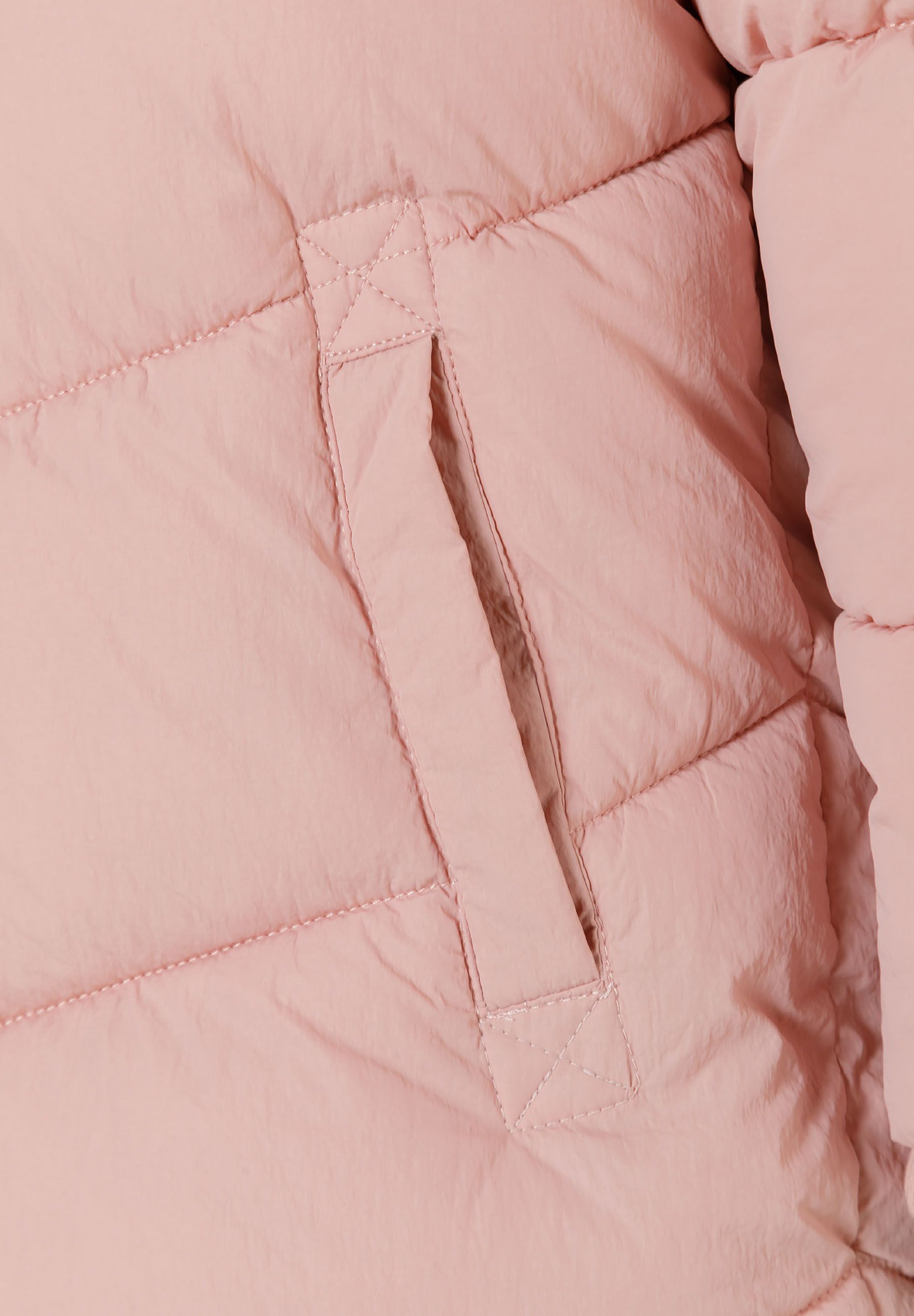 Detail of a pink girls long quilted winter jacket showing a side pocket.