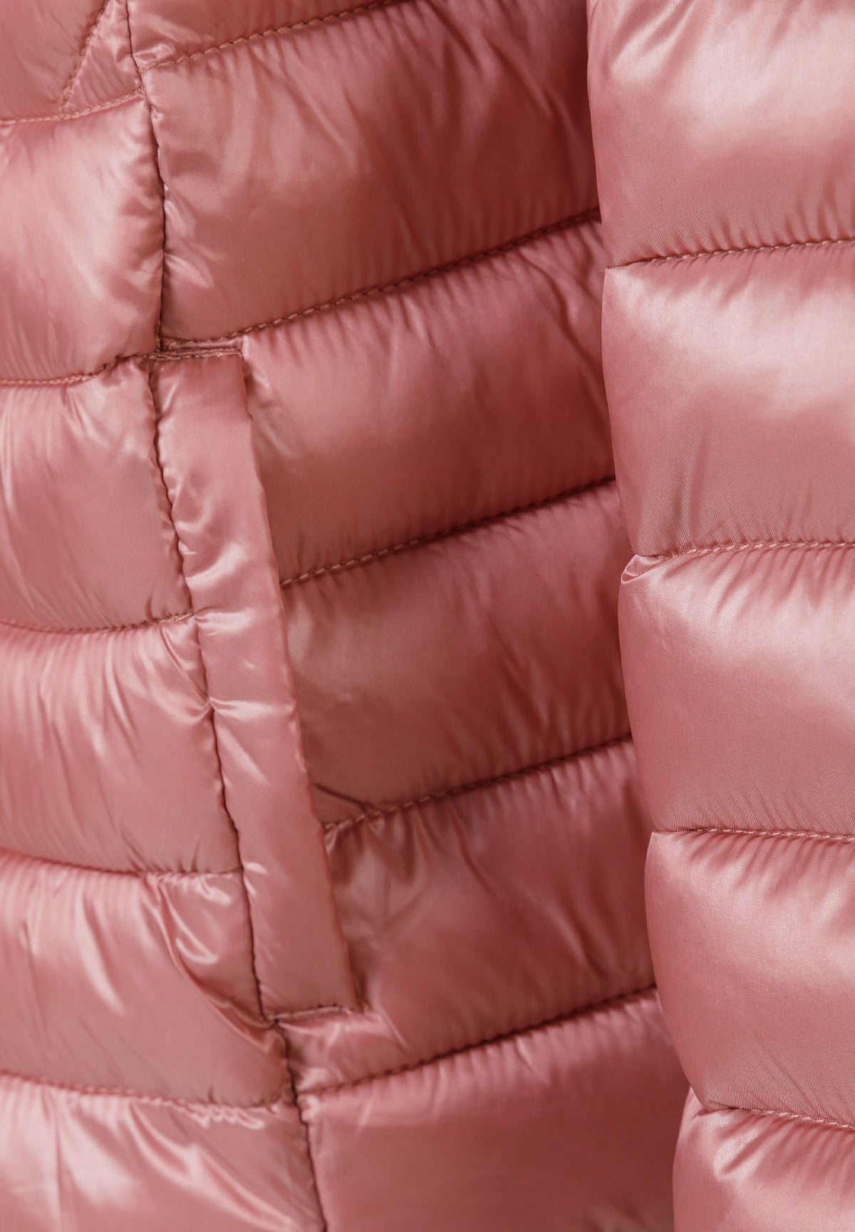 Close-up of the pocket on the dusky pink puffer jacket.