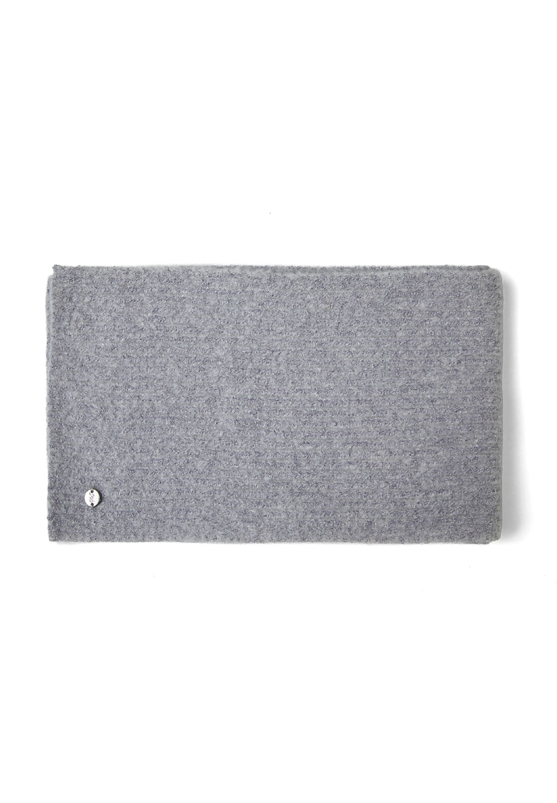Detail of a grey ribbed knit hat with a metal badge.