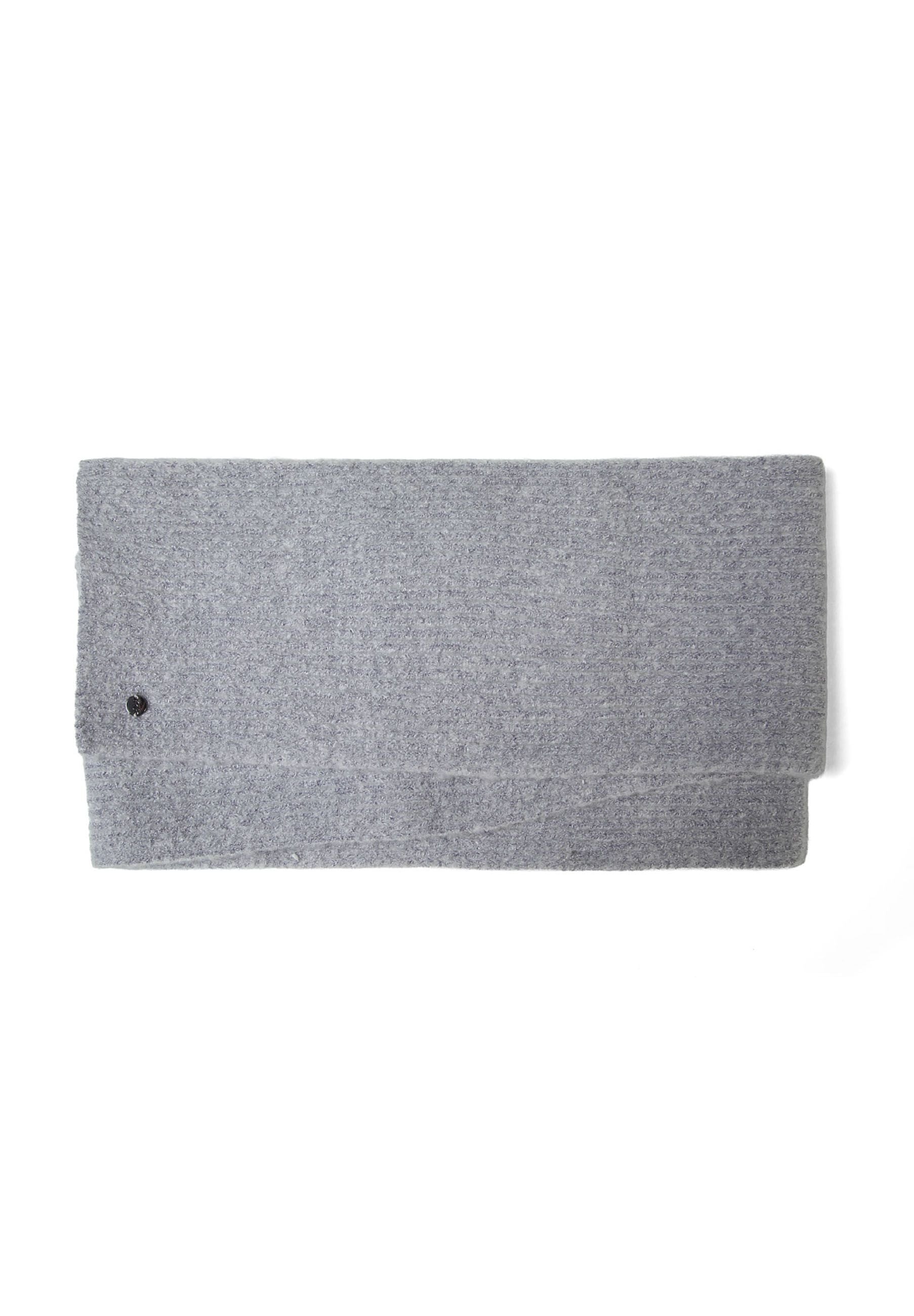 Detail of a grey ribbed knit scarf with a metal badge.