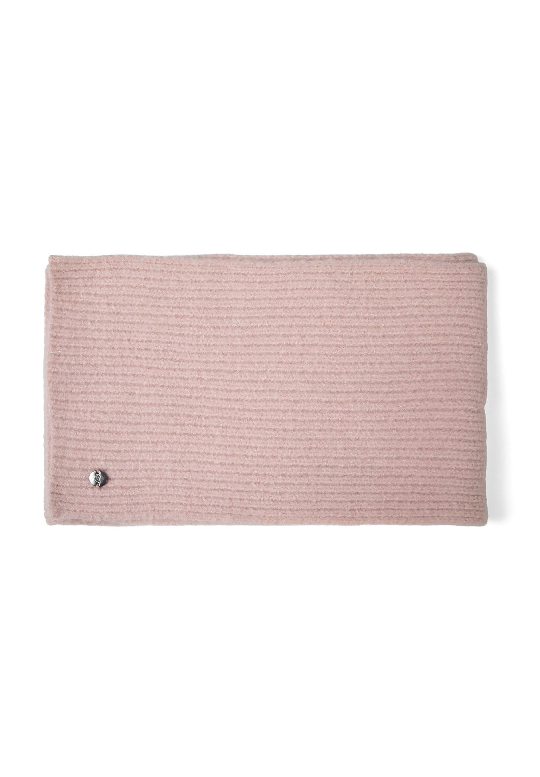 Detail of a pink ribbed knit hat with a soft pompom and metal badge.