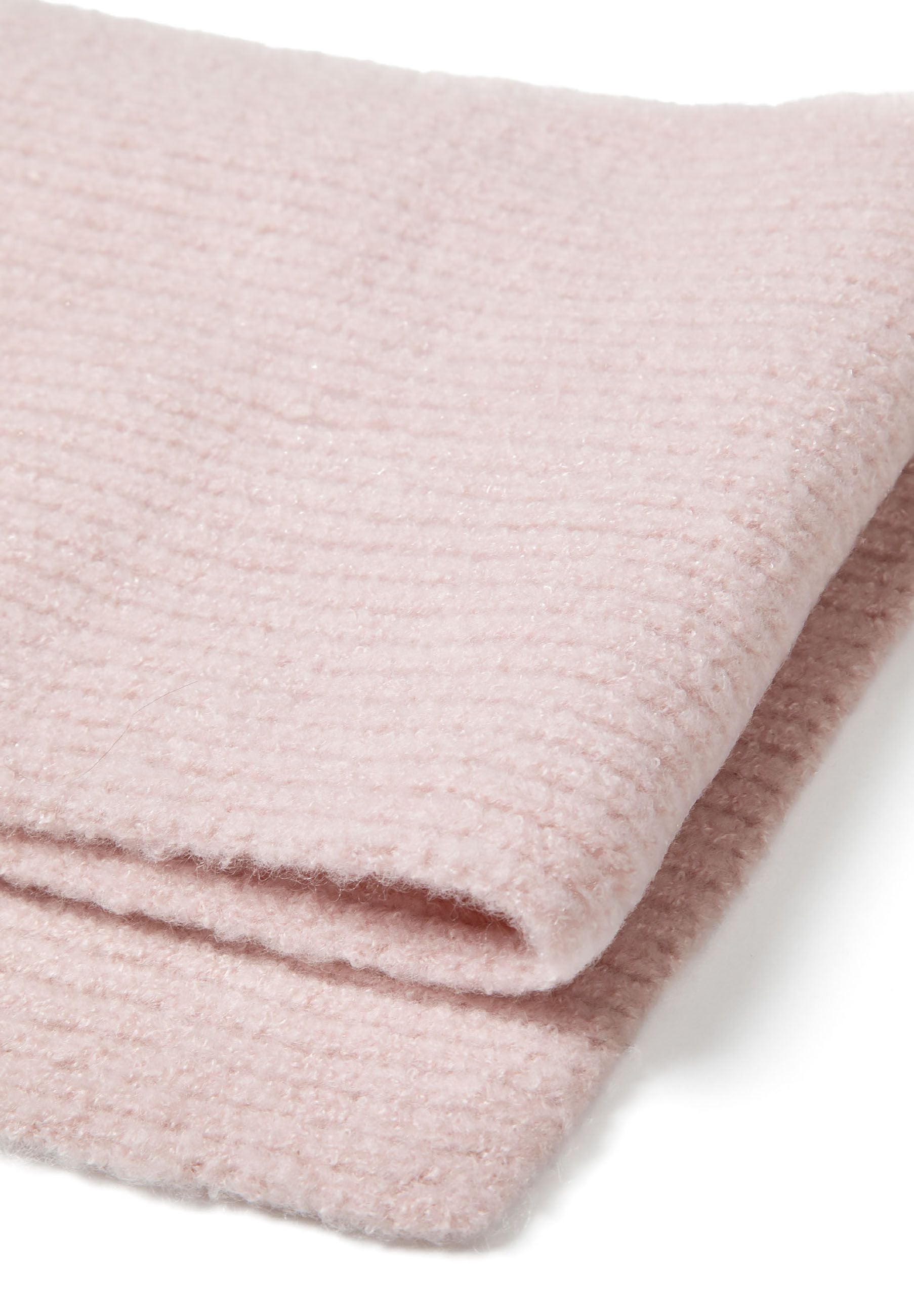 Detail of a pink ribbed knit hat with a metal badge.