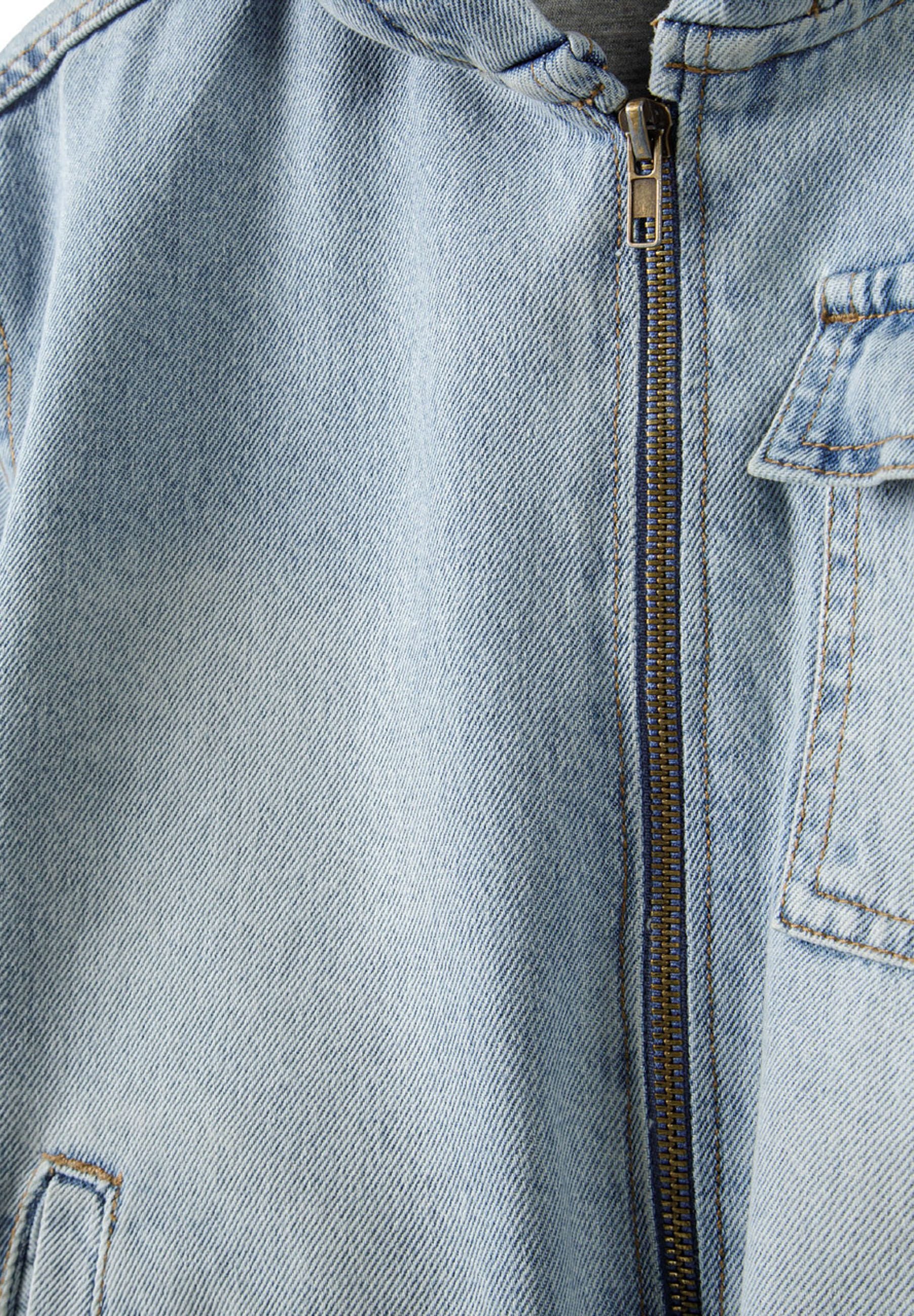 Detail of boys light blue denim jacket with hood and zip fastening.