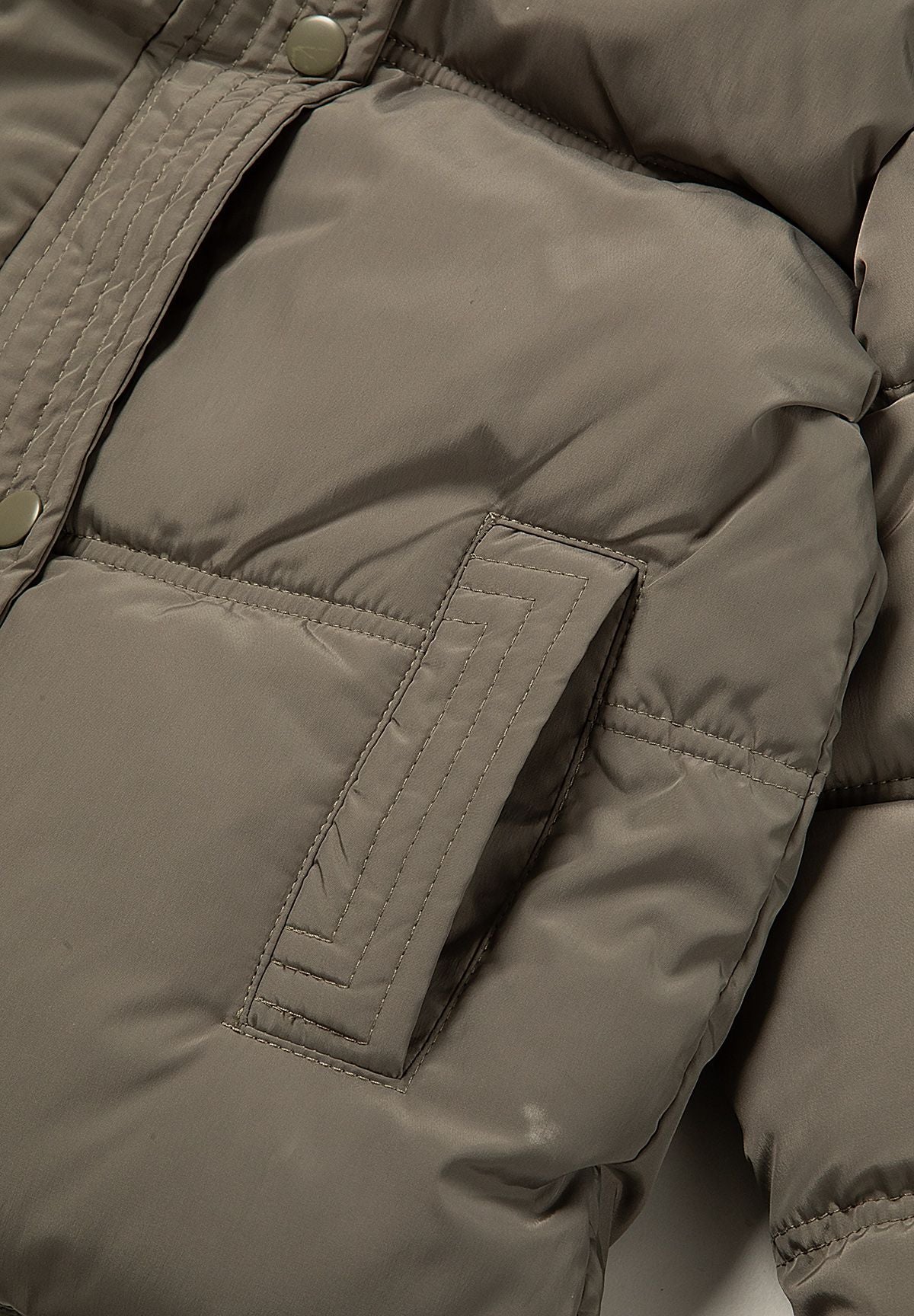 Close-up of a vertical welt-style pocket set into the khaki padded jacket.