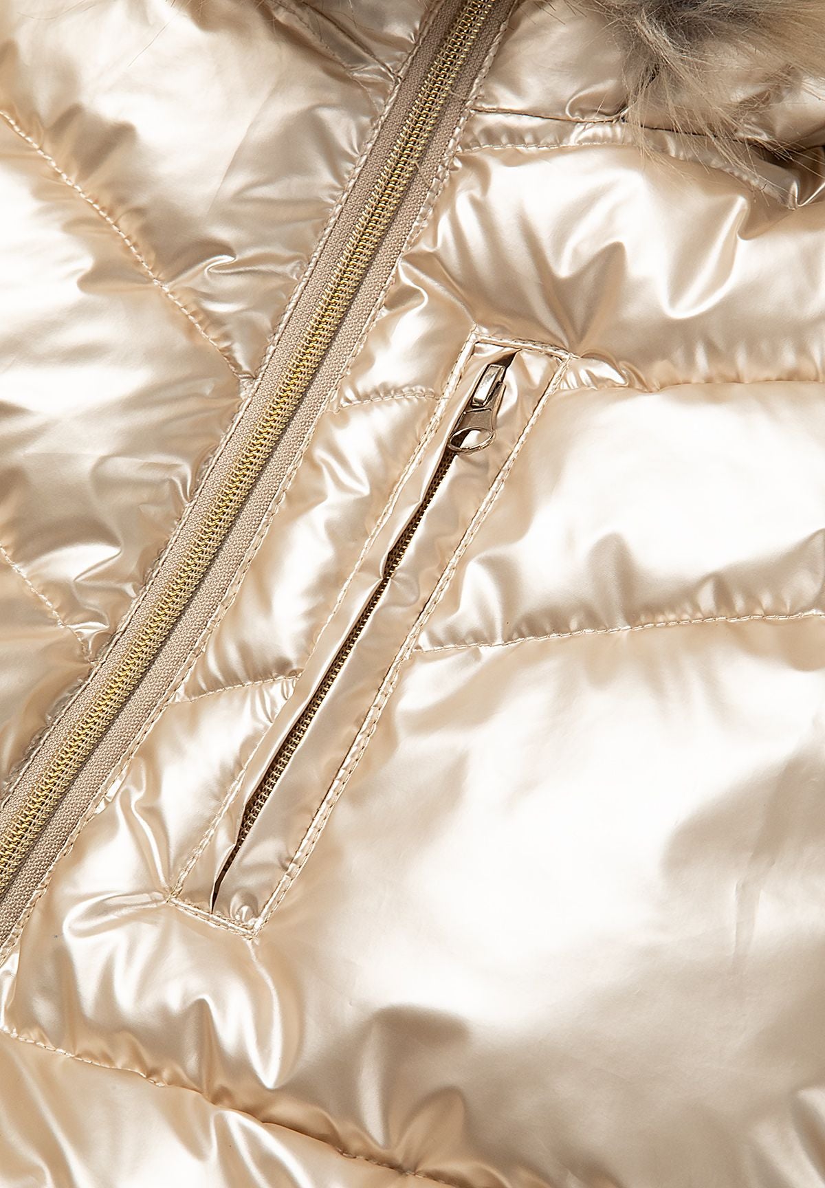 Manteau matelassé métallisé doré pour fille avec capuche en fausse fourrure, gros plan sur la fermeture éclair.