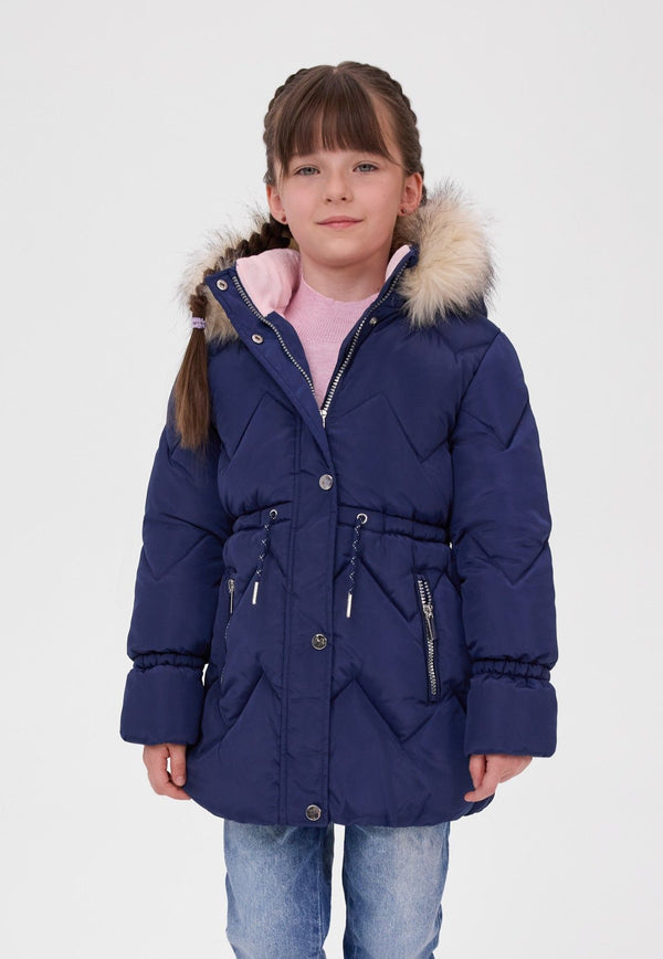 Girl wearing a navy padded coat with cream fluffy hood trim, gathered waist and zipped front pockets.
