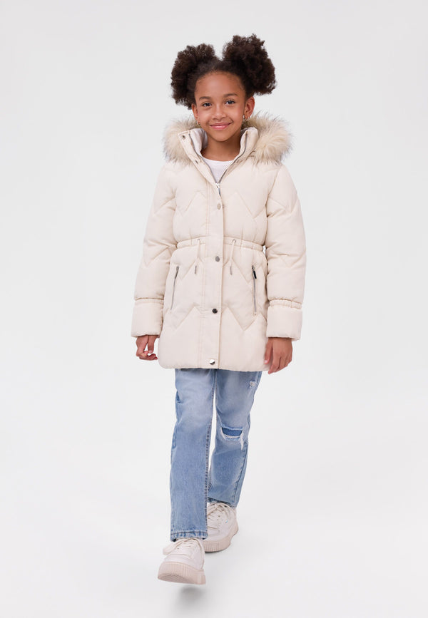 Girl wearing a cream quilted coat with fluffy hood trim, gathered waist and zipped pockets.