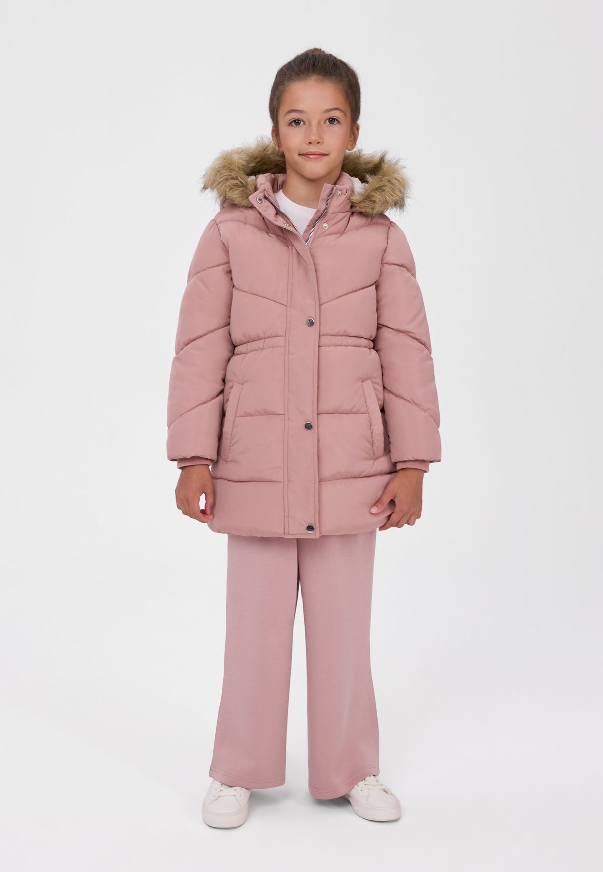 Girl wearing a dusty pink quilted coat with a brown fluffy hood trim, gathered waist and long snap-front placket.