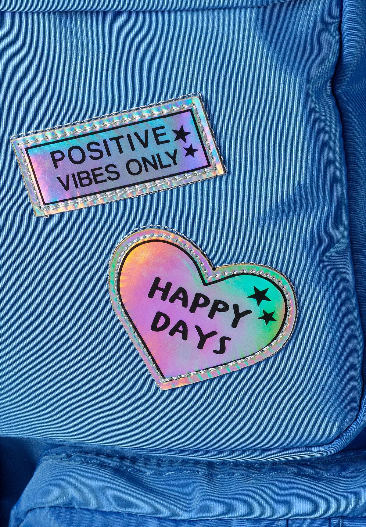 Blauwe rugzak voor meisjes met glanzende badges, detail van de glanzende badges.
