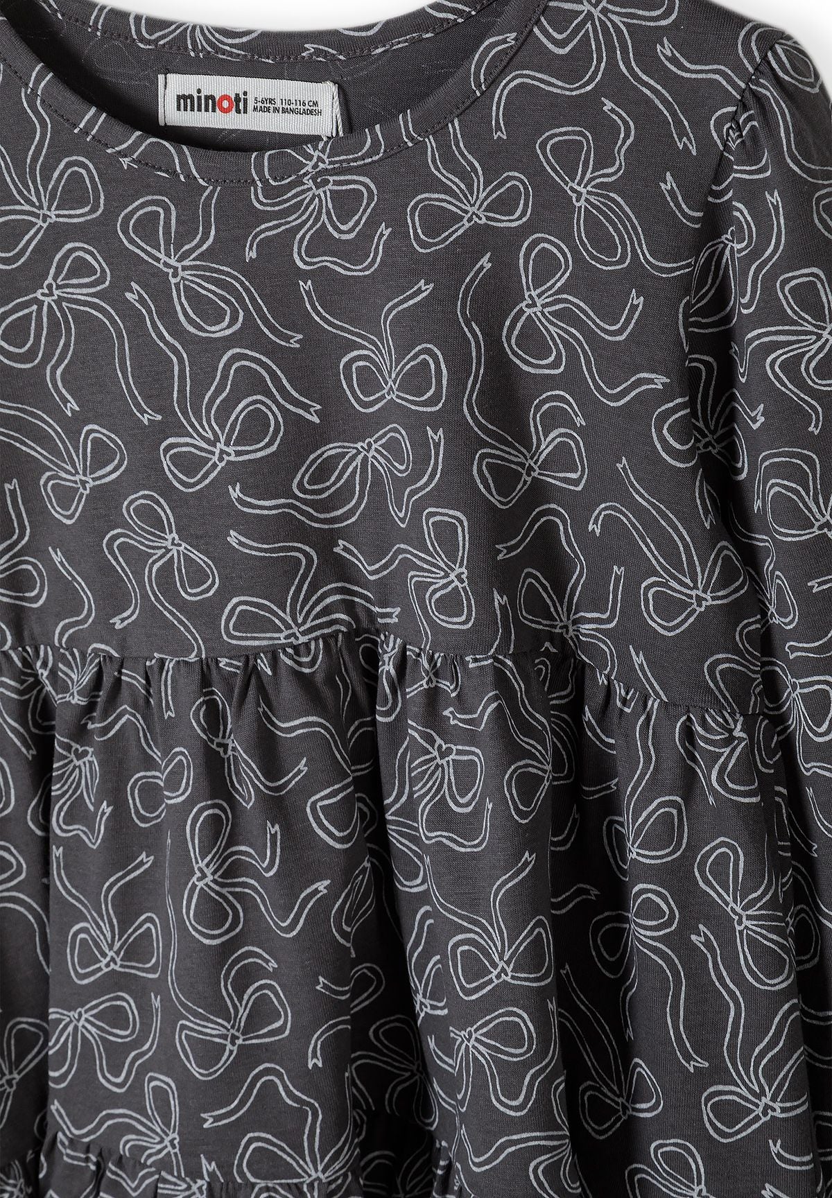 Close-up of white outline bow print on charcoal tiered dress.