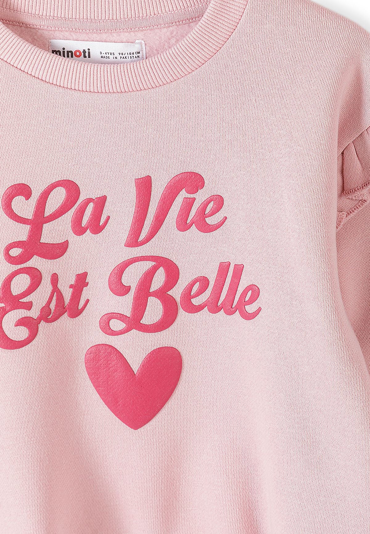 Survêtement rose à volants pour fille, composé d’un sweat-shirt et d’un pantalon de jogging, gros plan sur l’imprimé « La Vie Est Belle ».