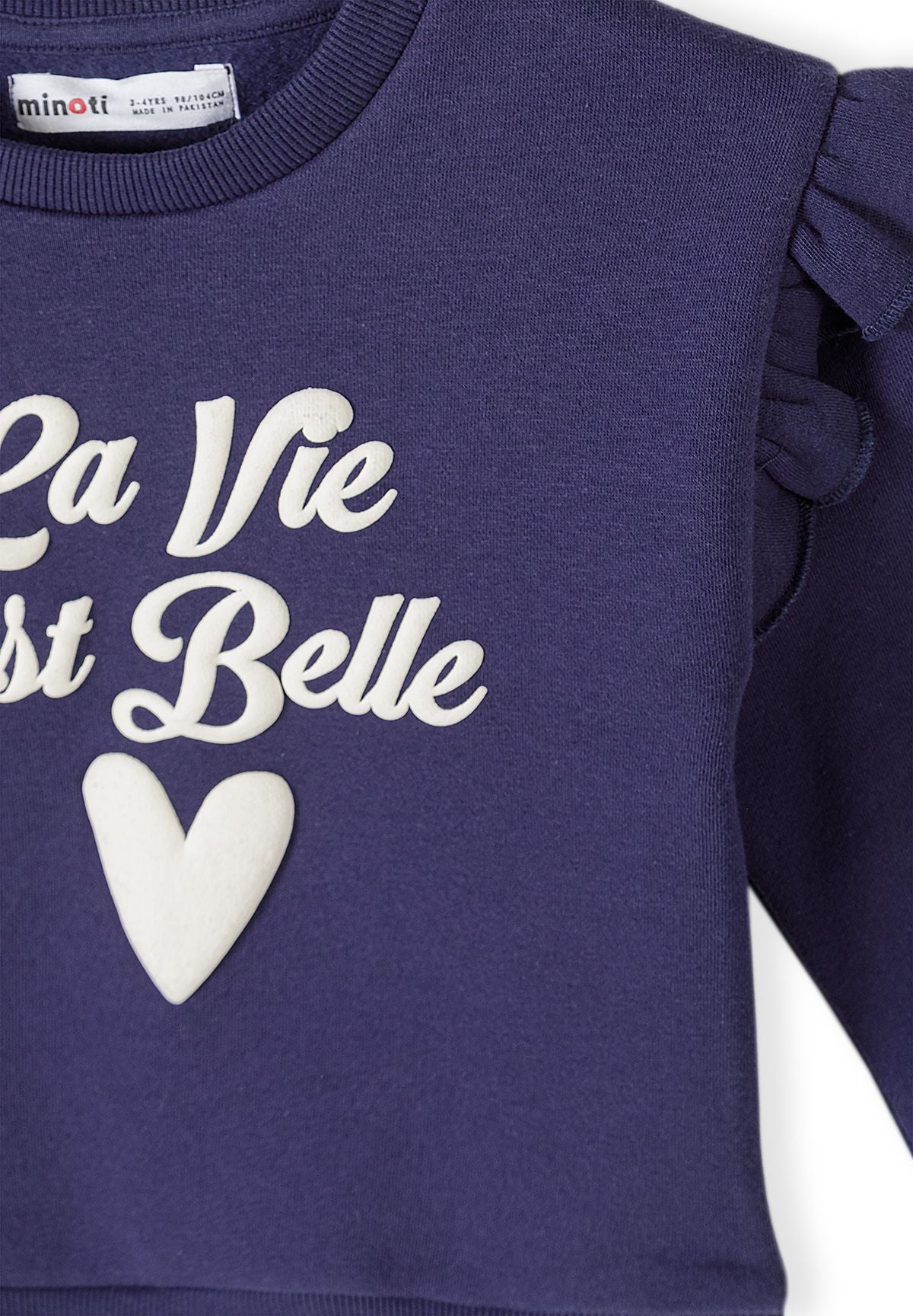 Survêtement pour fille composé d'un sweat-shirt bleu foncé à volants et d'un pantalon de jogging, gros plan sur l'imprimé « La Vie Est Belle ».