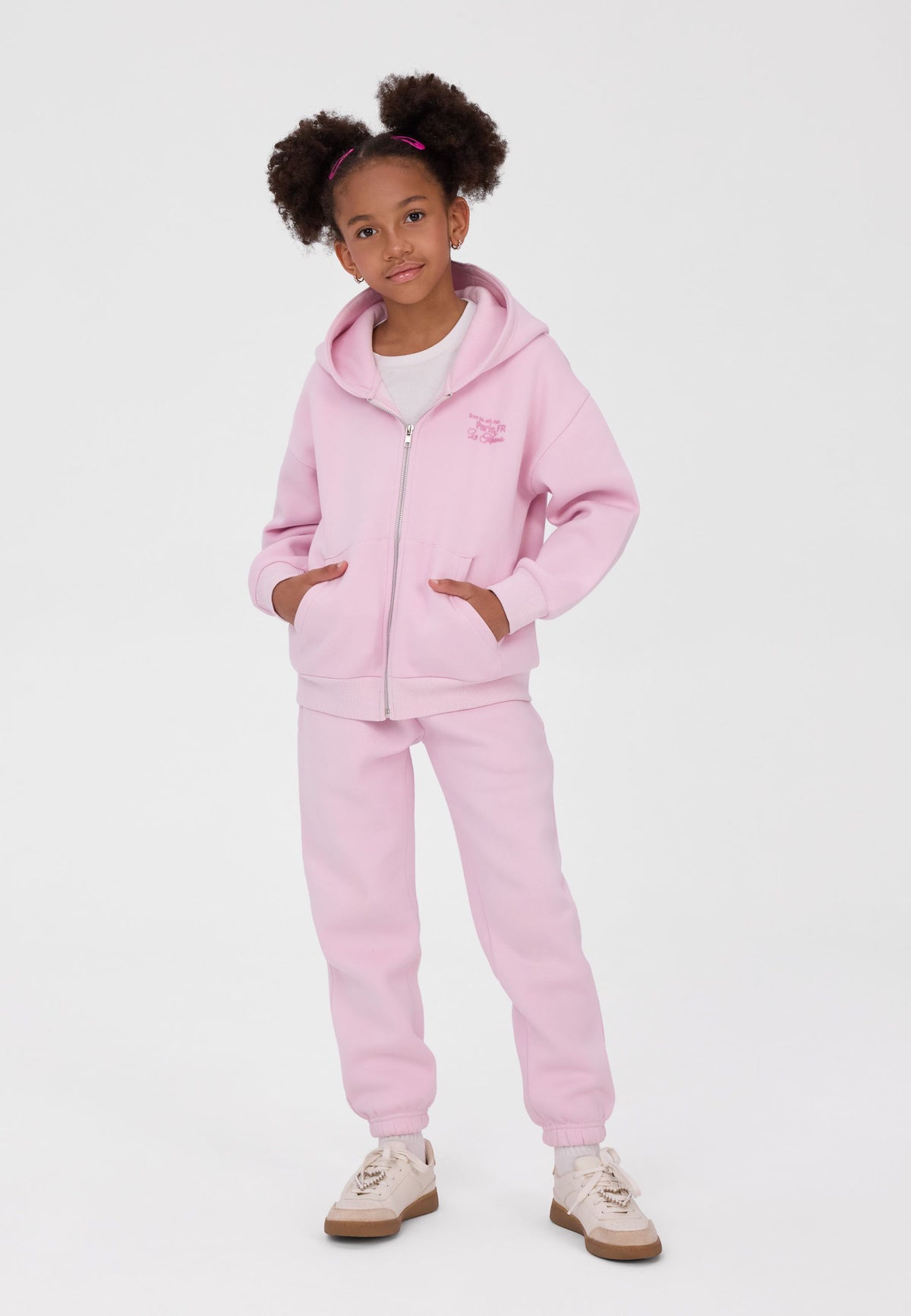Pantaloni da jogging da bambina con risvolto in nero, bianco e rosa (confezione da 3), modello in primo piano con i pantaloni rosa.