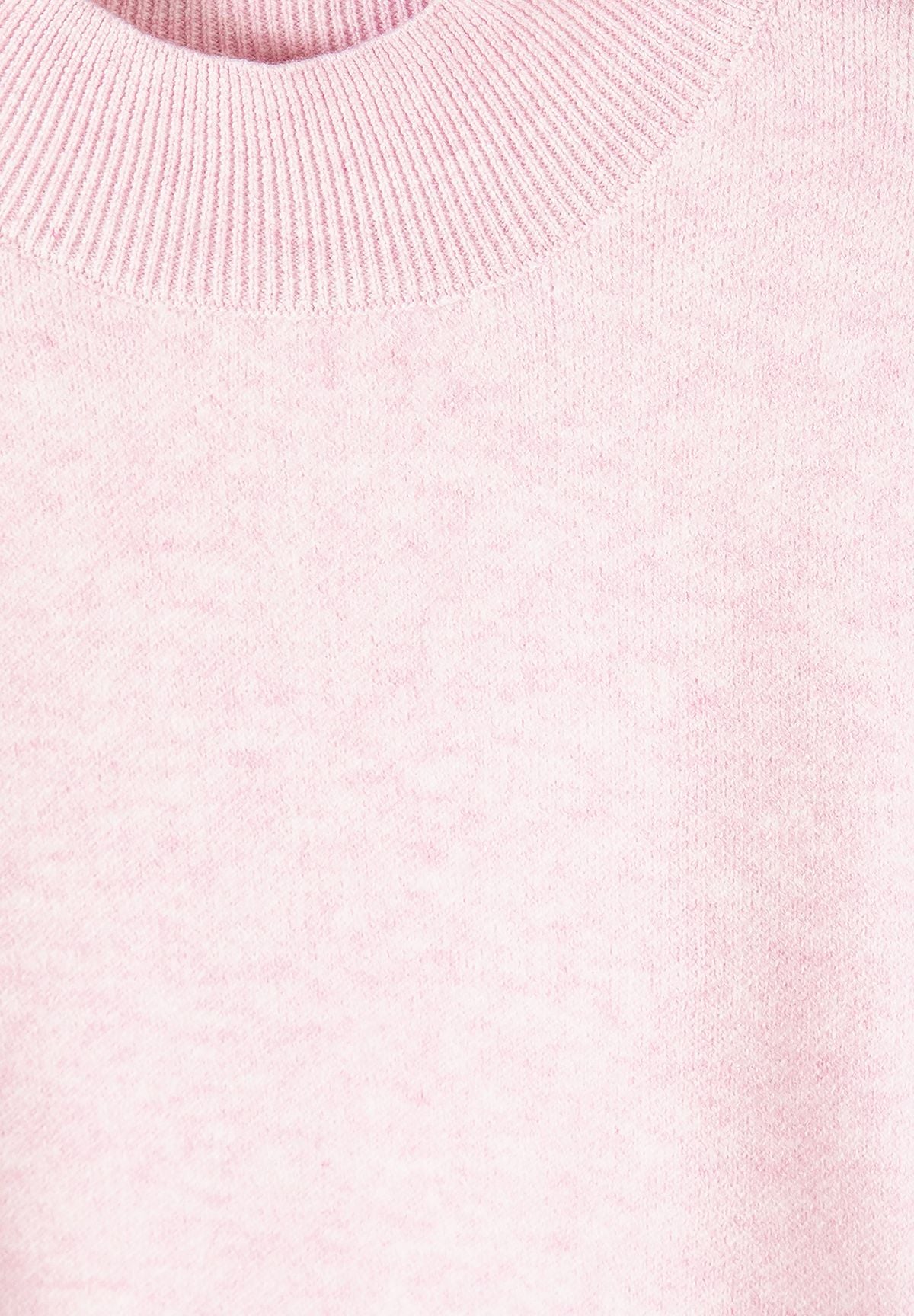 Close-up of pale pink jumper's short high ribbed neck and softly mottled knit surface.