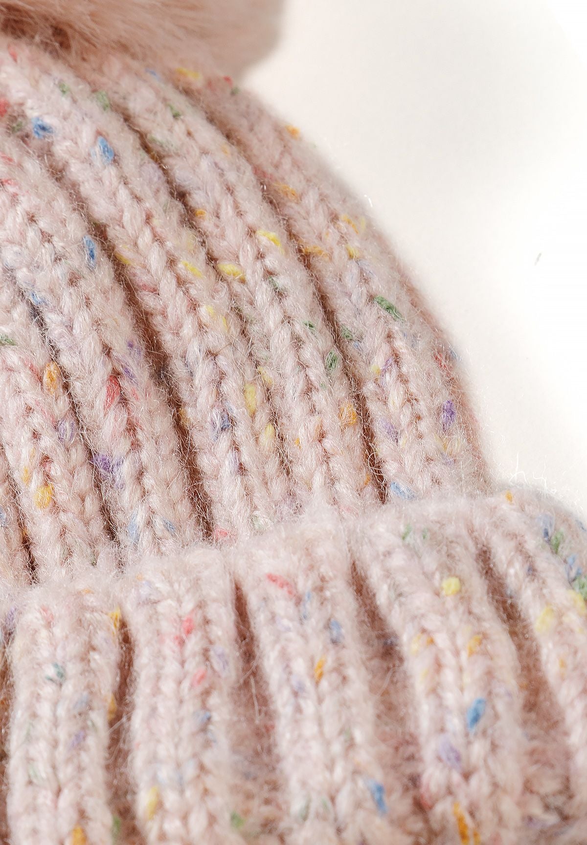 Bonnet à pompon rose moucheté pour fille, gros plan sur le tricot moucheté.