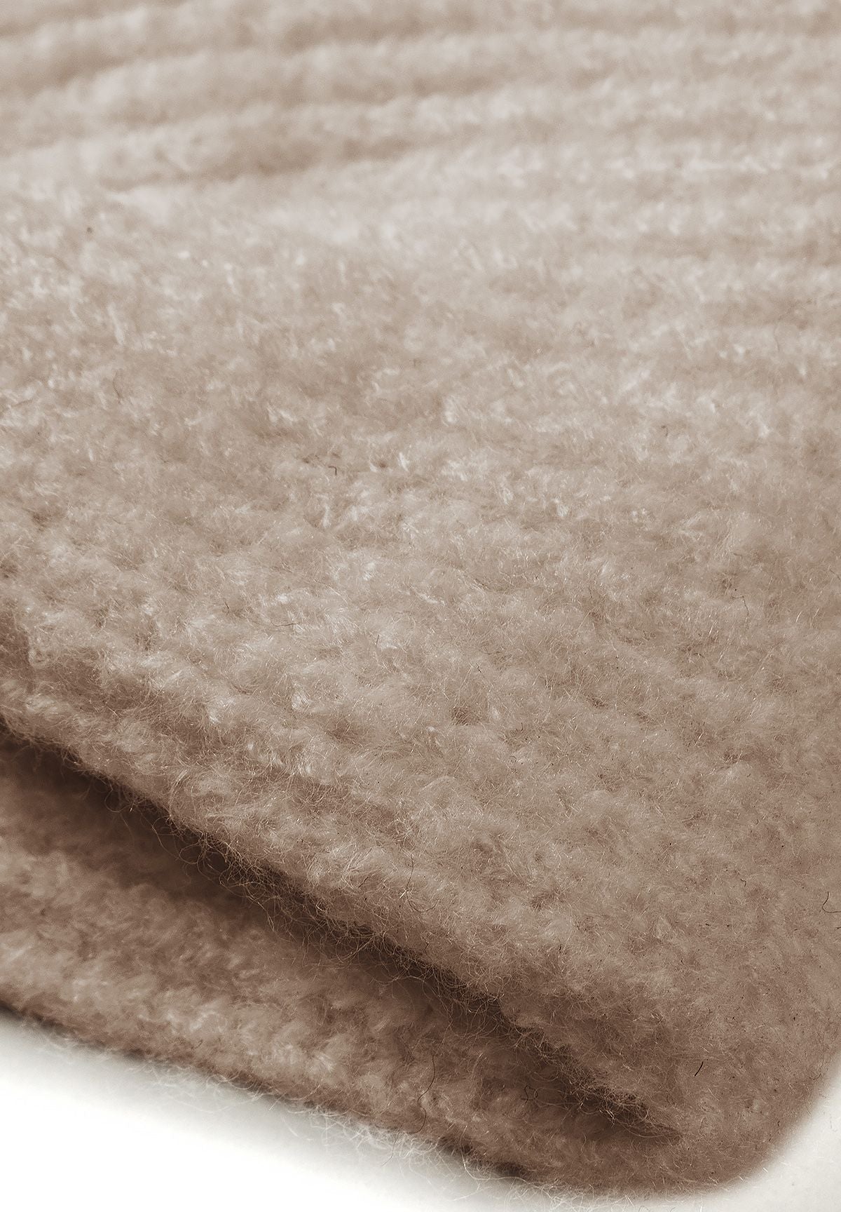 Close-up of the warm beige headband's soft knit texture and folded edge.