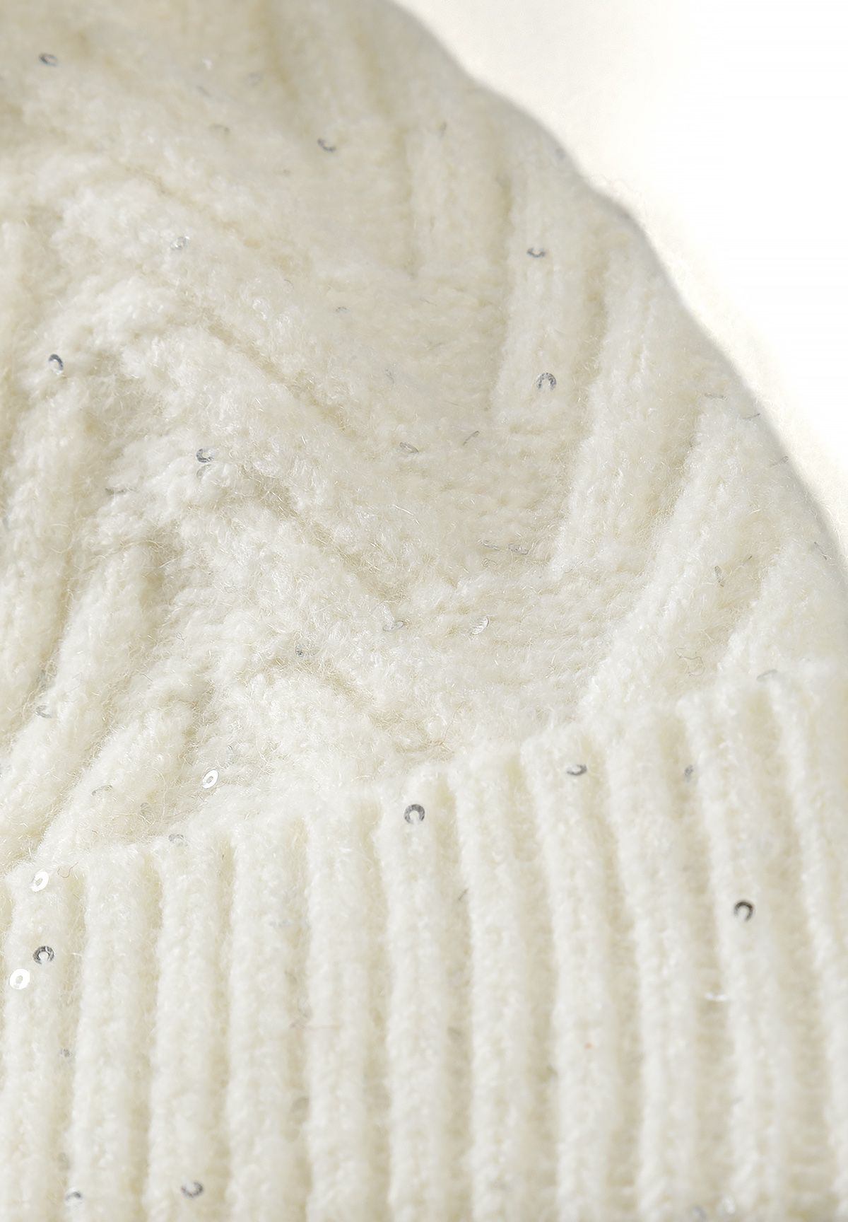 Close-up of the cream snood's raised chevron stitches, ribbing and tiny silver sequins.