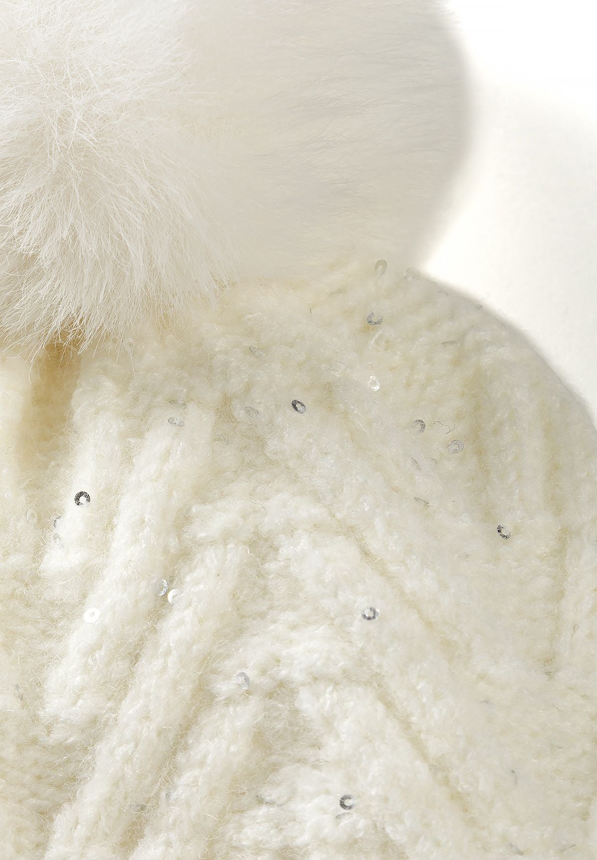 Close-up of the cream beanie's fluffy pale pom and sequined chevron knit below.
