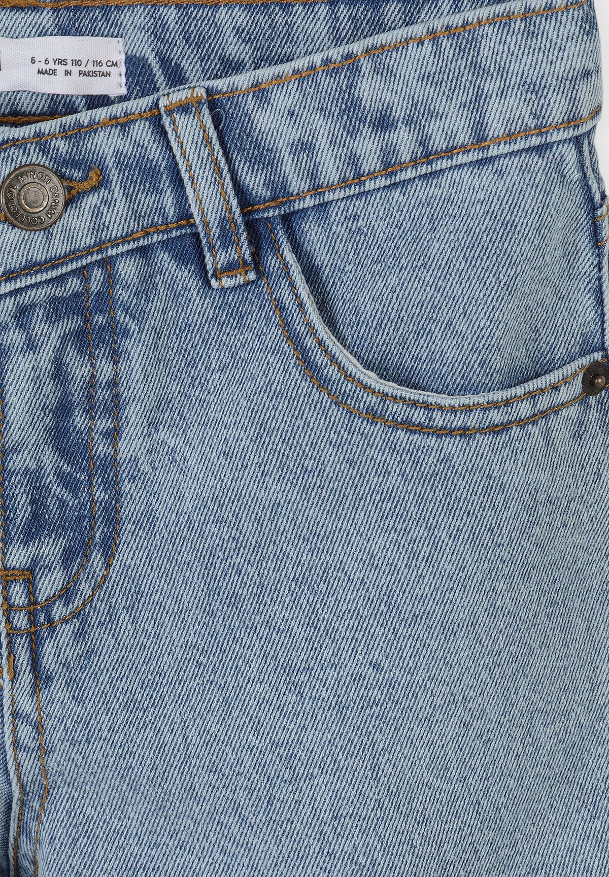 Close-up of jeans waistband with metal button, belt loop and curved front pocket in washed blue denim.