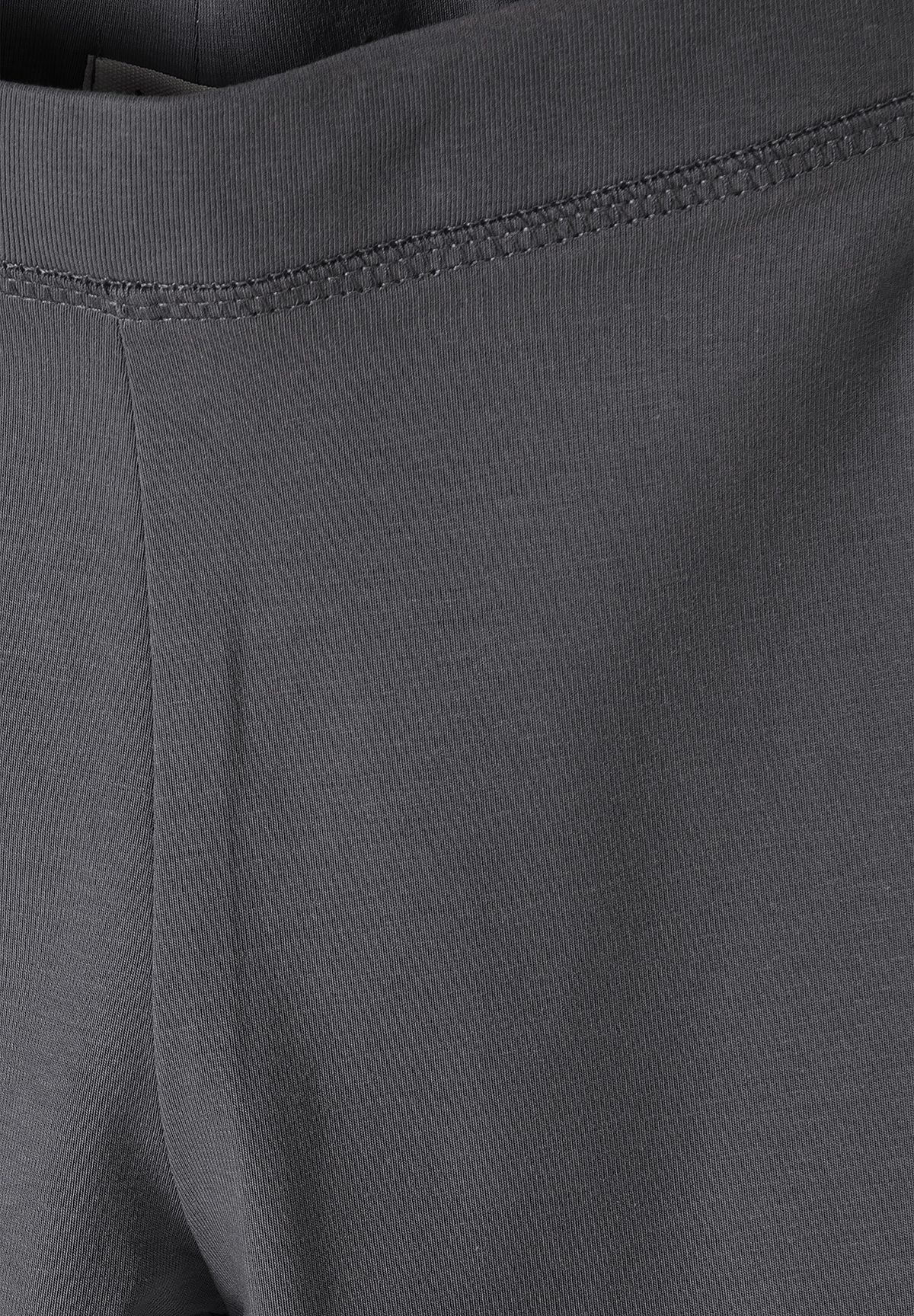 Close-up of charcoal leggings' fine vertical rib fabric and waistband seam.