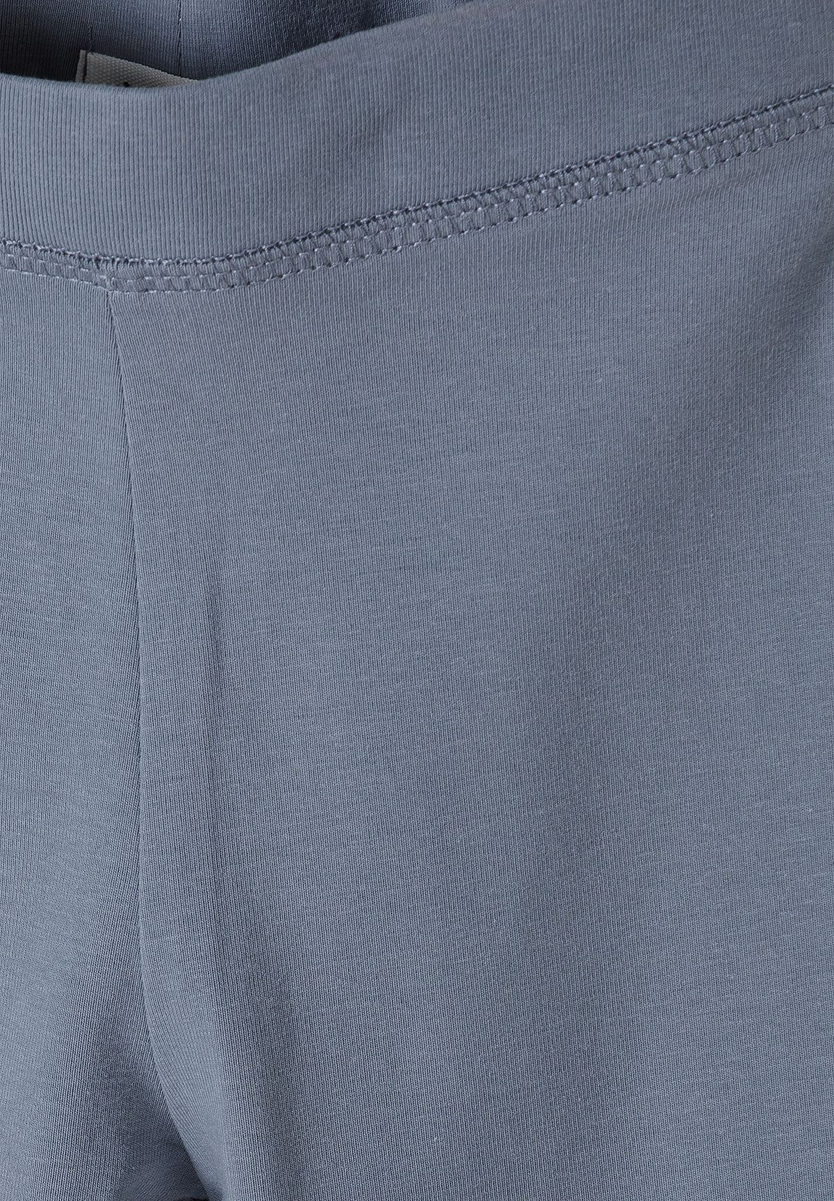 Close-up of blue leggings' fine rib texture and stitched waistband.
