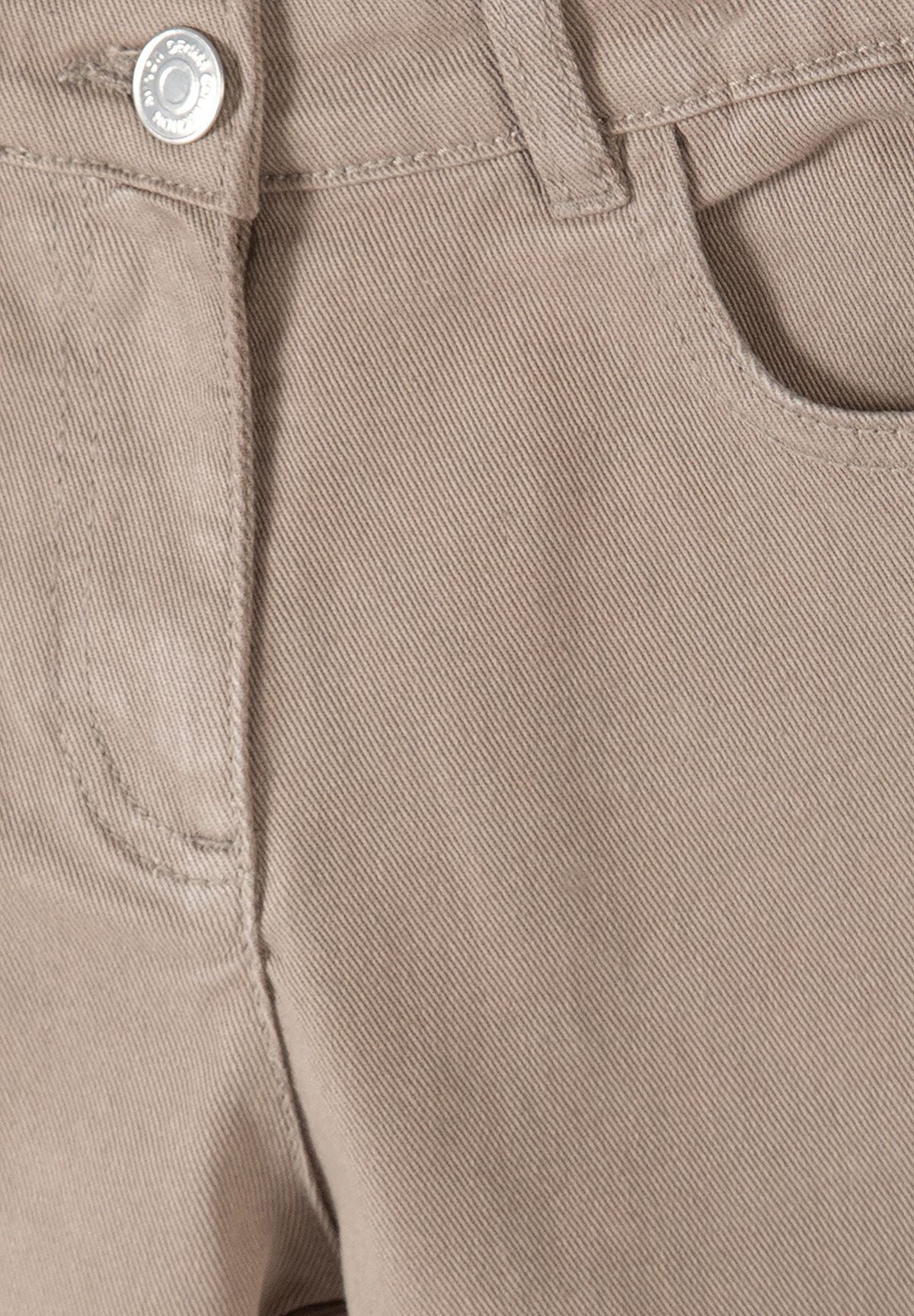 Beigefarbene Hose mit weitem Bein für Mädchen, Nahaufnahme des Bunds und der Tasche.