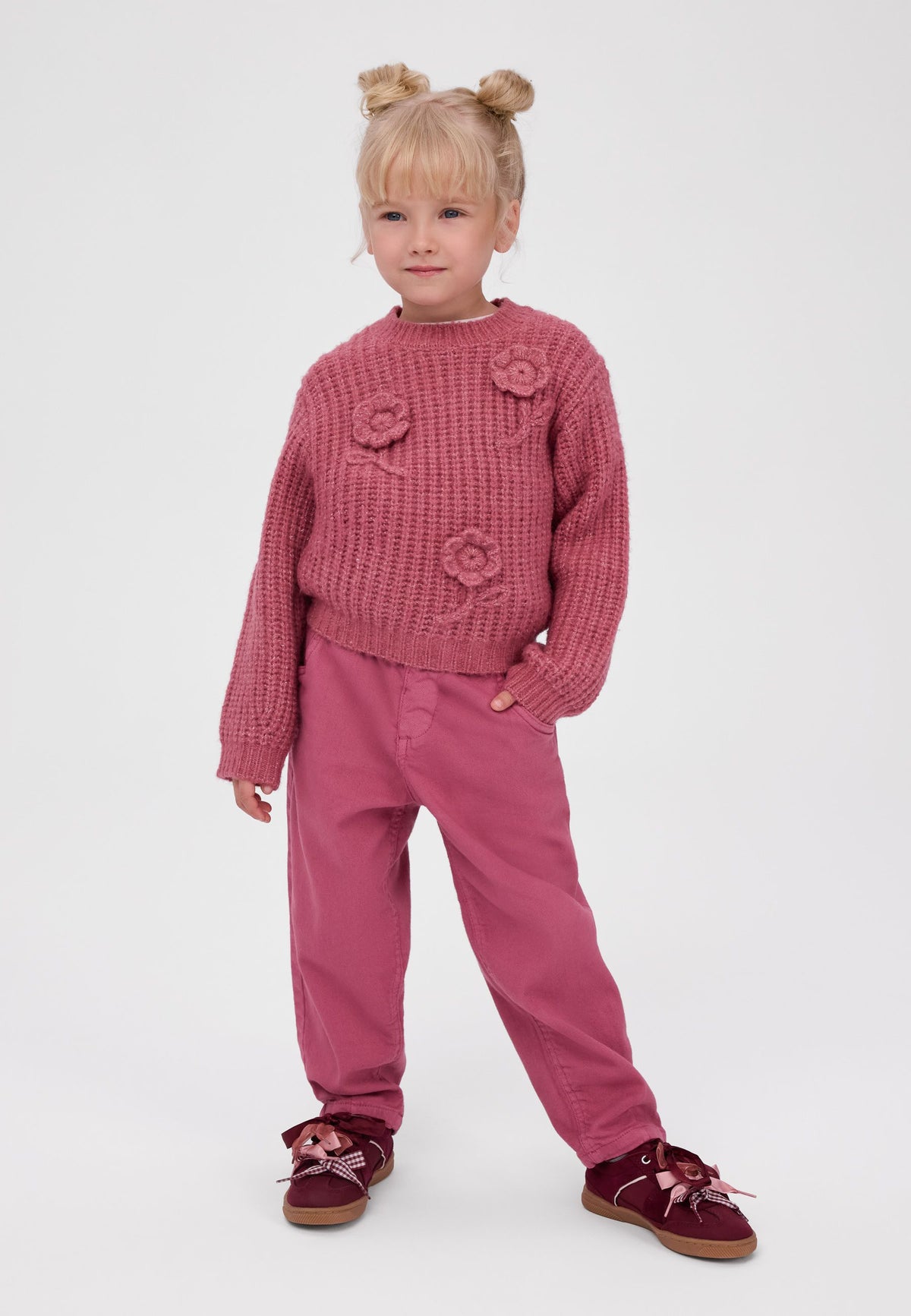 Girl wearing dusty pink paperbag-waist trousers with curved pockets.