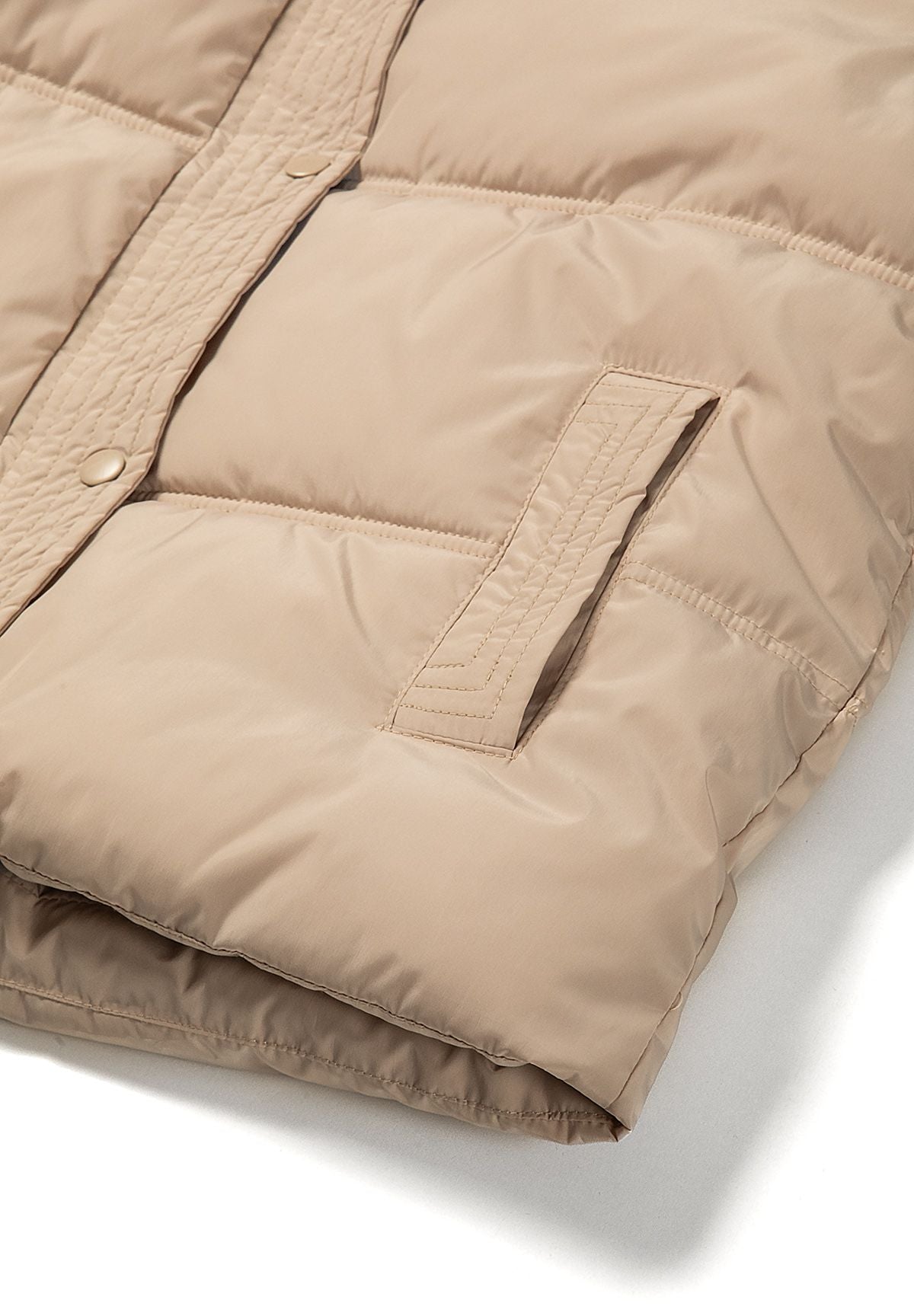 Women's short puffer jacket in beige with hood, close-up of the front pocket
