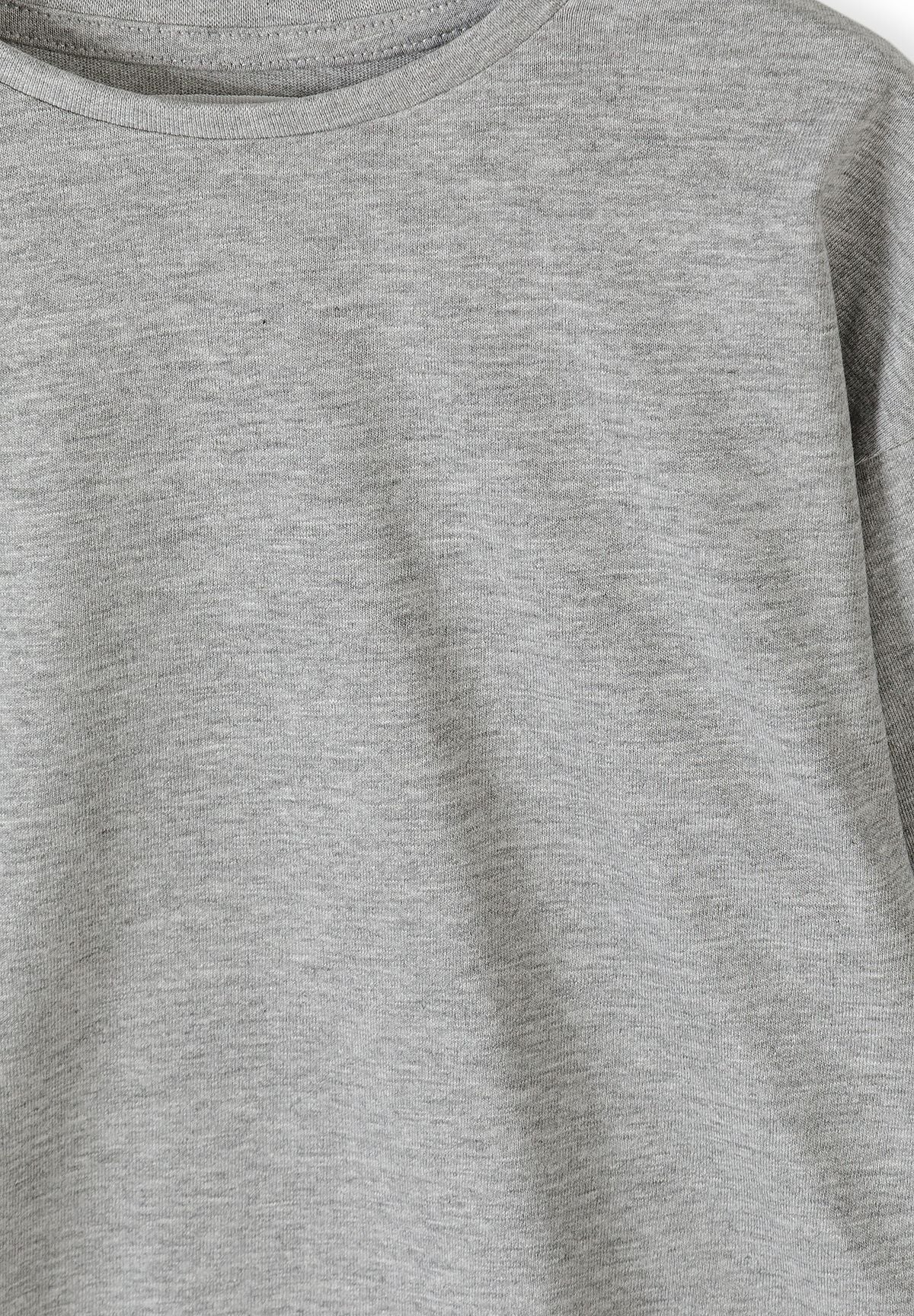 Close-up of grey marl fabric and crew neckline on plain top.