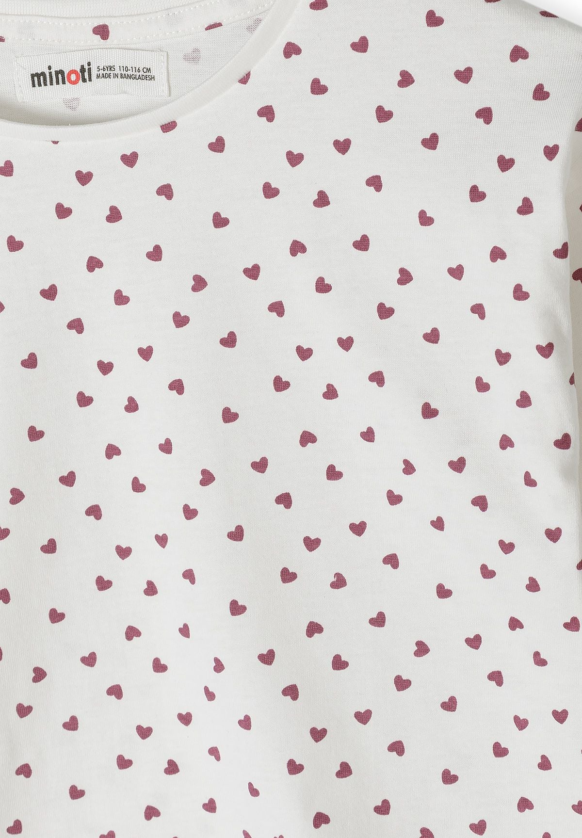 Close-up of small berry hearts on white long-sleeve top.