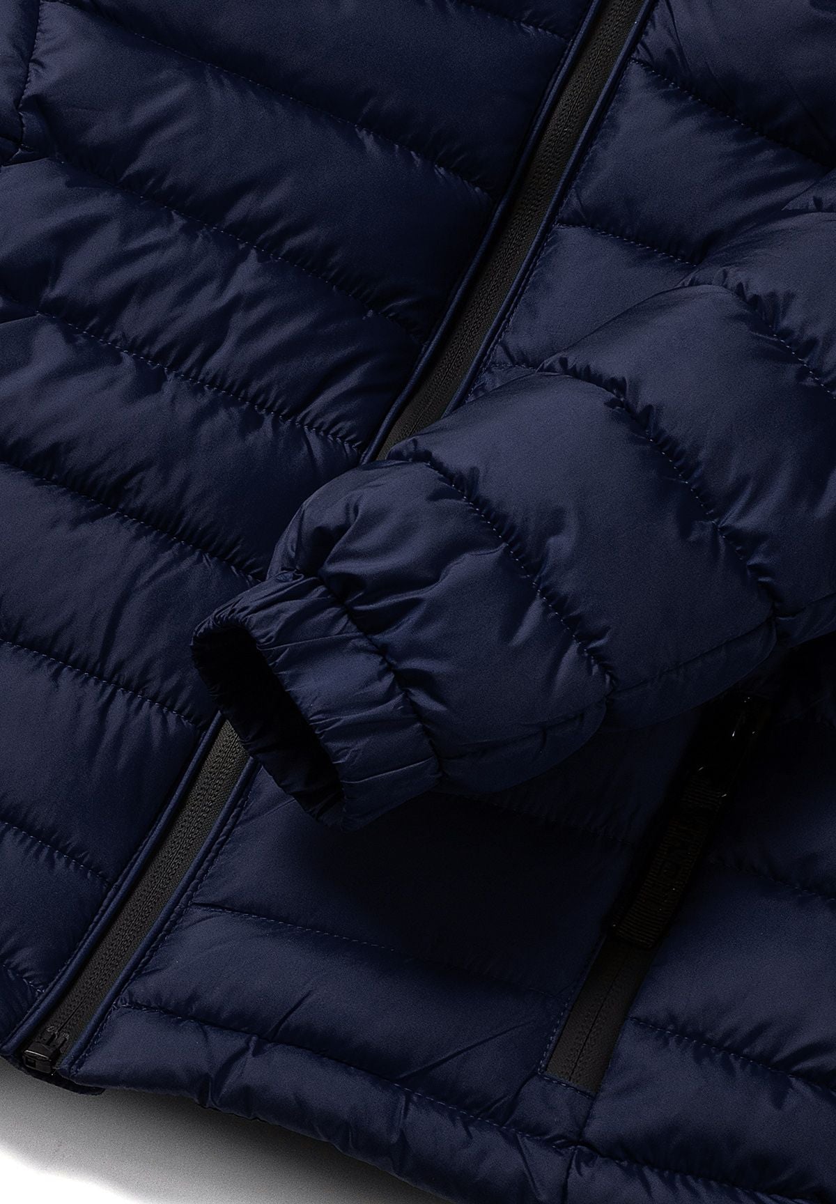 Donkerblauwe pufferjas met capuchon voor jongens, met een logo-opdruk op de rug, detail van de manchet.
