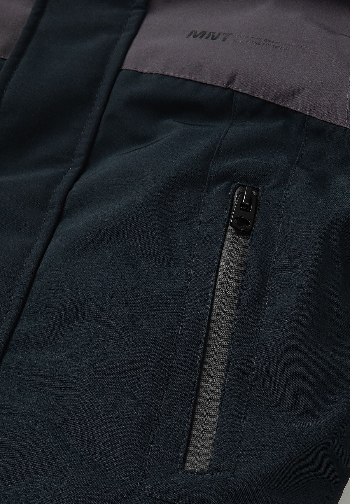 Close-up of a long vertical black hip-pocket zip below the parka's charcoal chest panel.