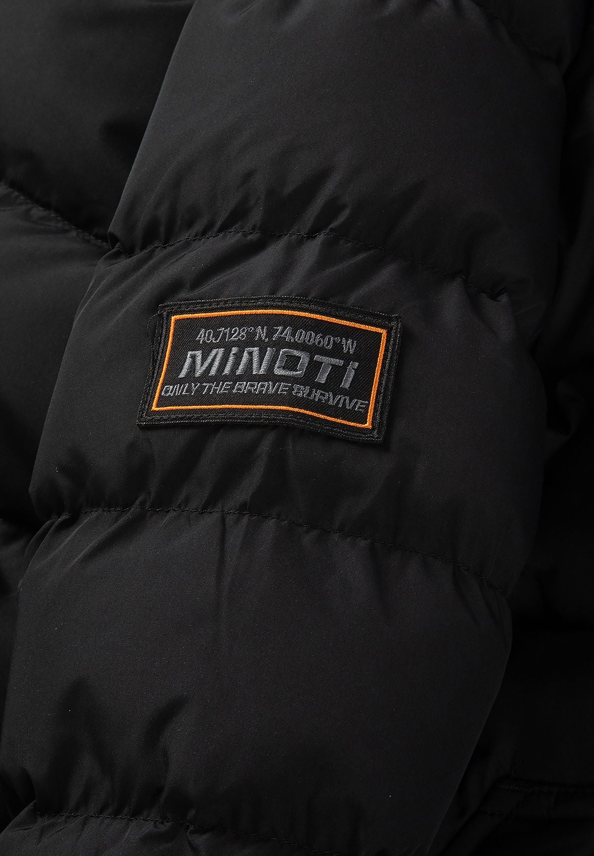 Zwarte gewatteerde parka voor jongens met afneembare capuchonrand, detail van het geweven embleem.