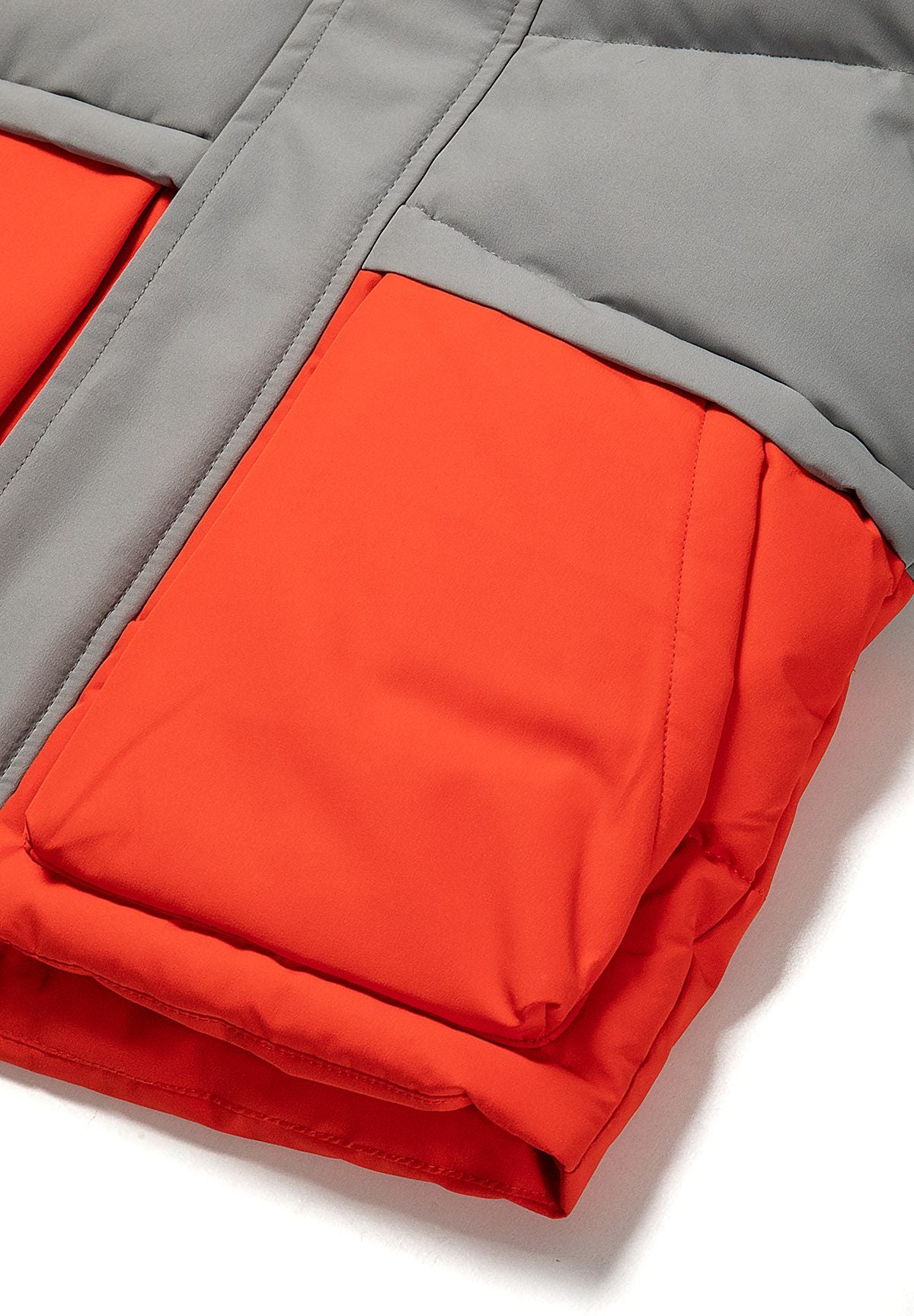 Grijze en rode gewatteerde parka met kleurblokken voor jongens, detail van de opgestikte zak.