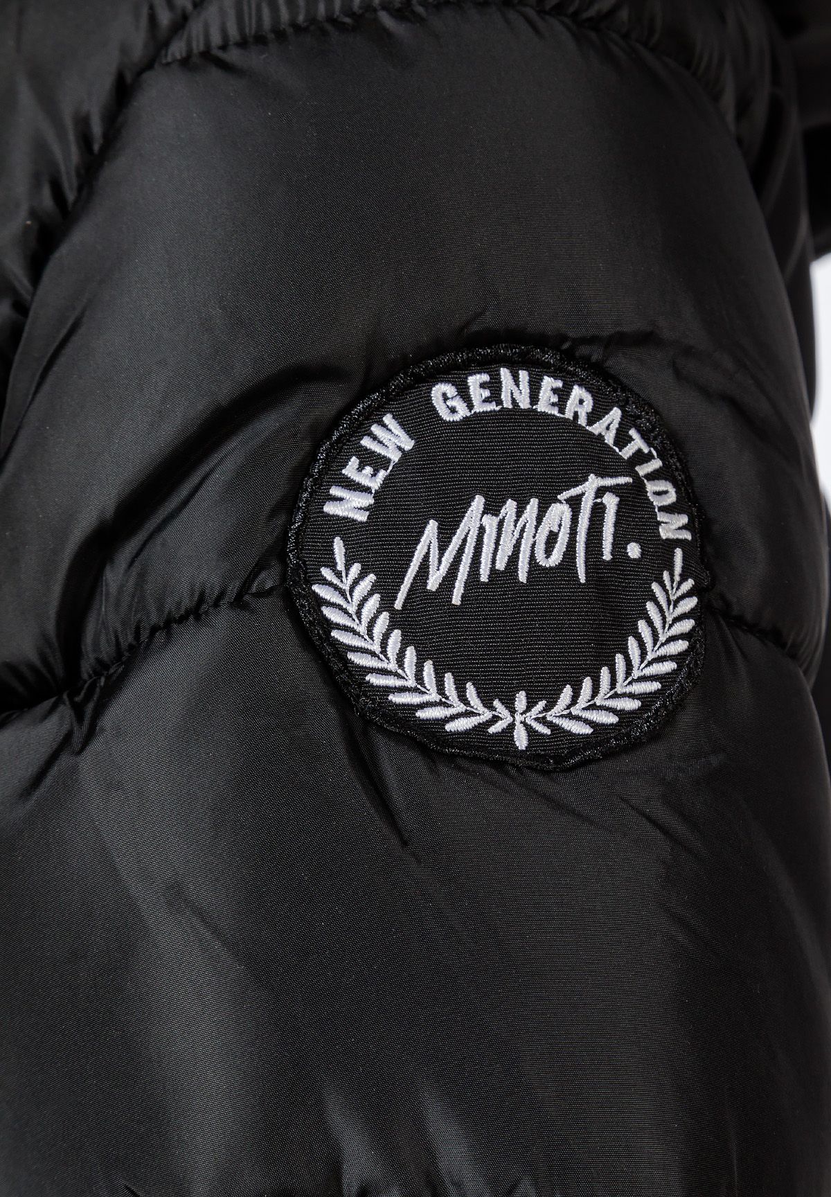 Circular black NEW GENERATION MINOTI badge with white laurel embroidery on the parka sleeve.