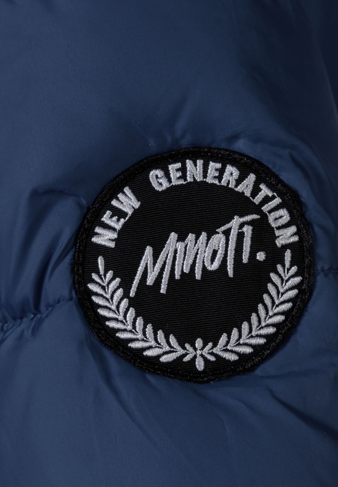 Close-up of the navy parka's round black NEW GENERATION MINOTI sleeve patch with white laurel design.