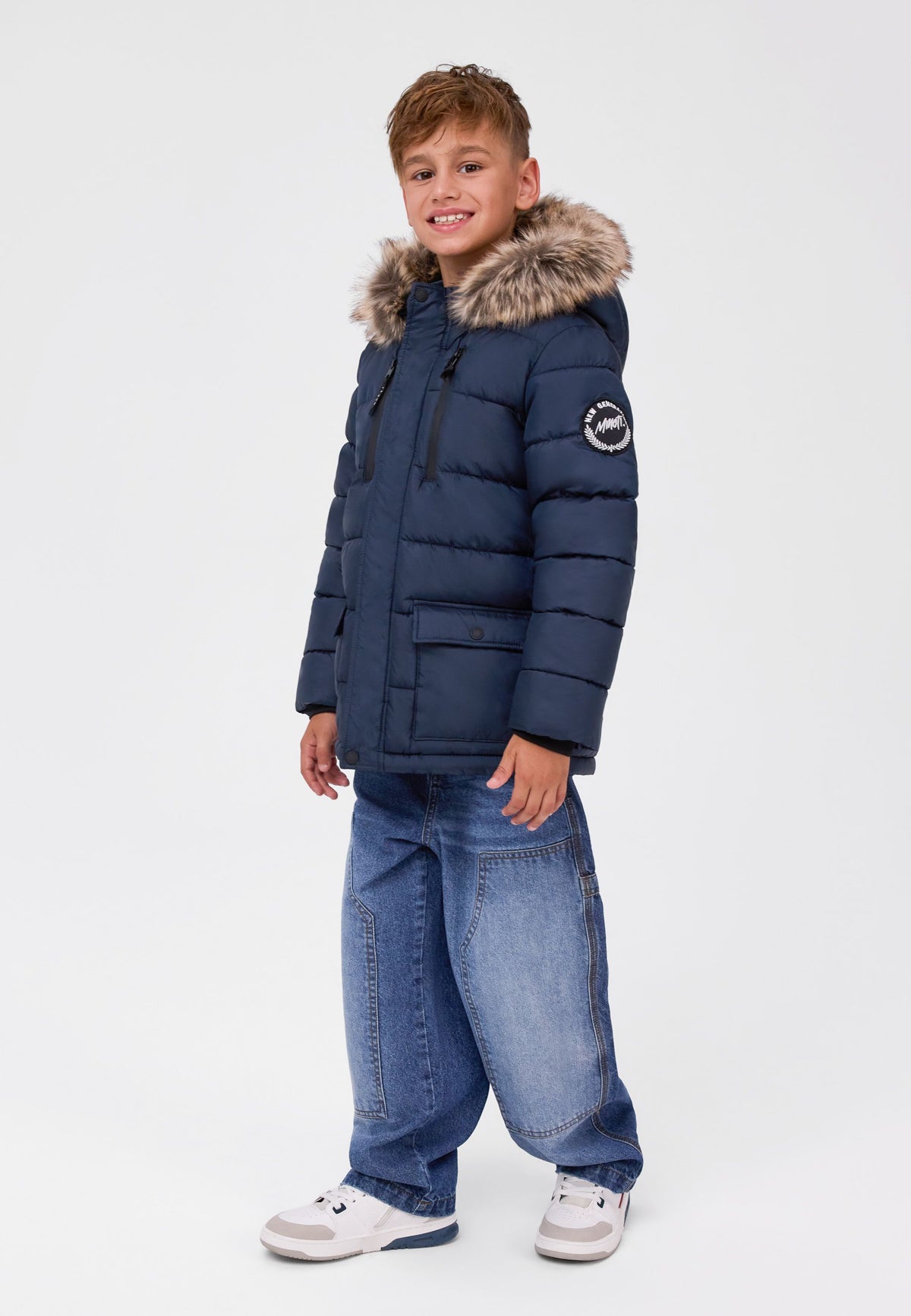 Boy wearing a navy padded parka with a fur-look hood, zipped chest pockets and lower flap pockets.