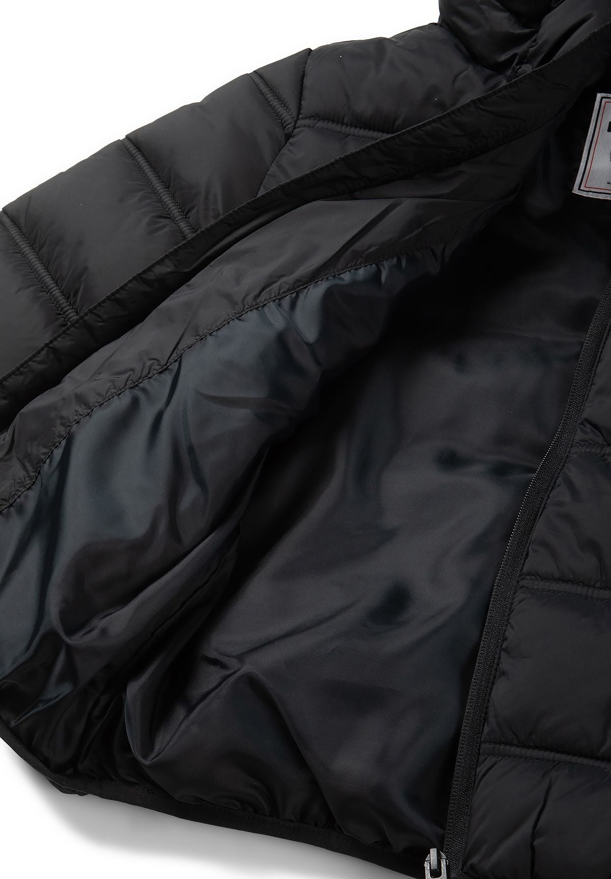 Inside of the black puffer jacket showing its smooth dark lining beside the quilted shell.