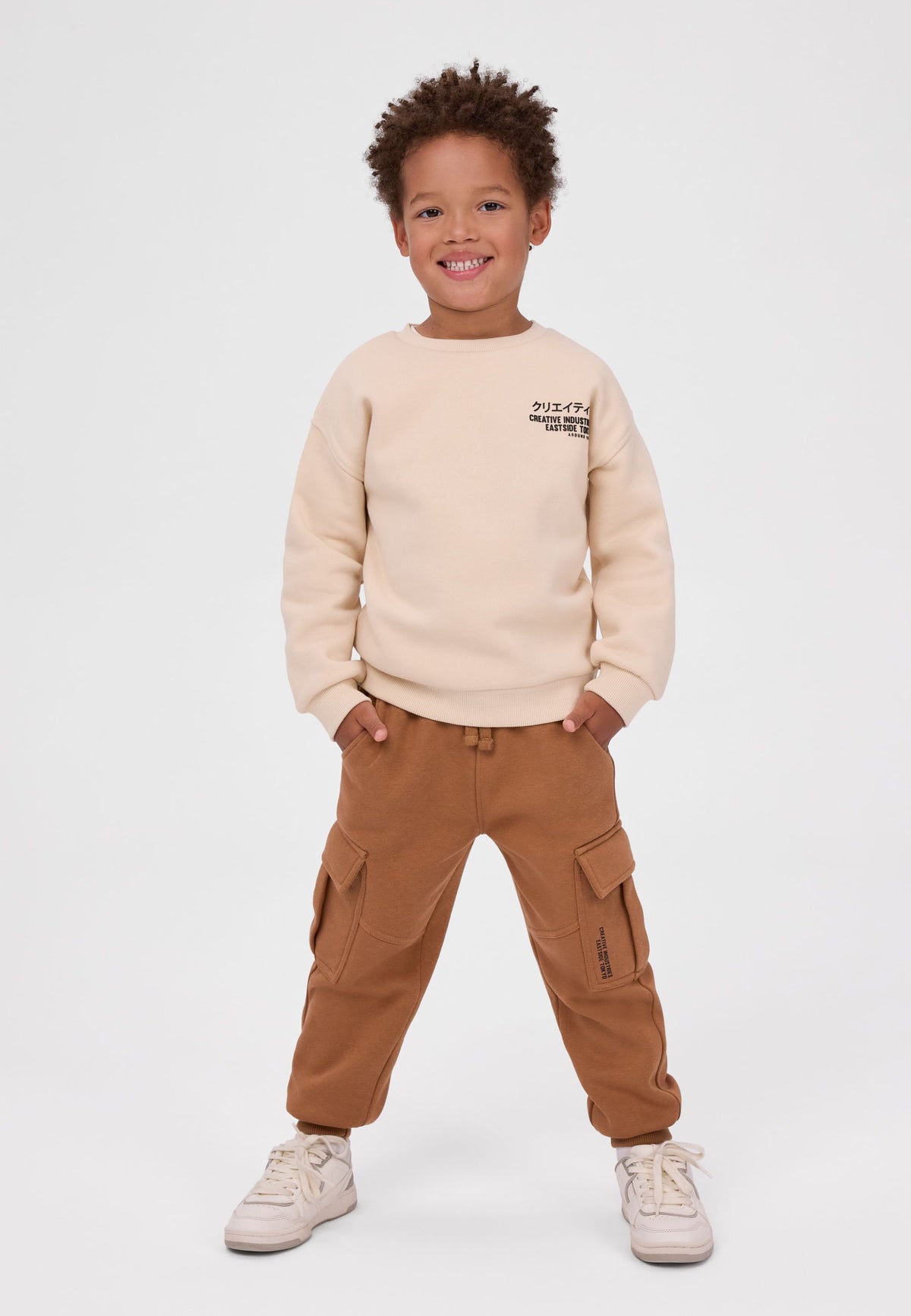 Crèmekleurige trainingsset voor jongens met sweatshirt en cargo-joggingbroek, vooraanzicht op model.