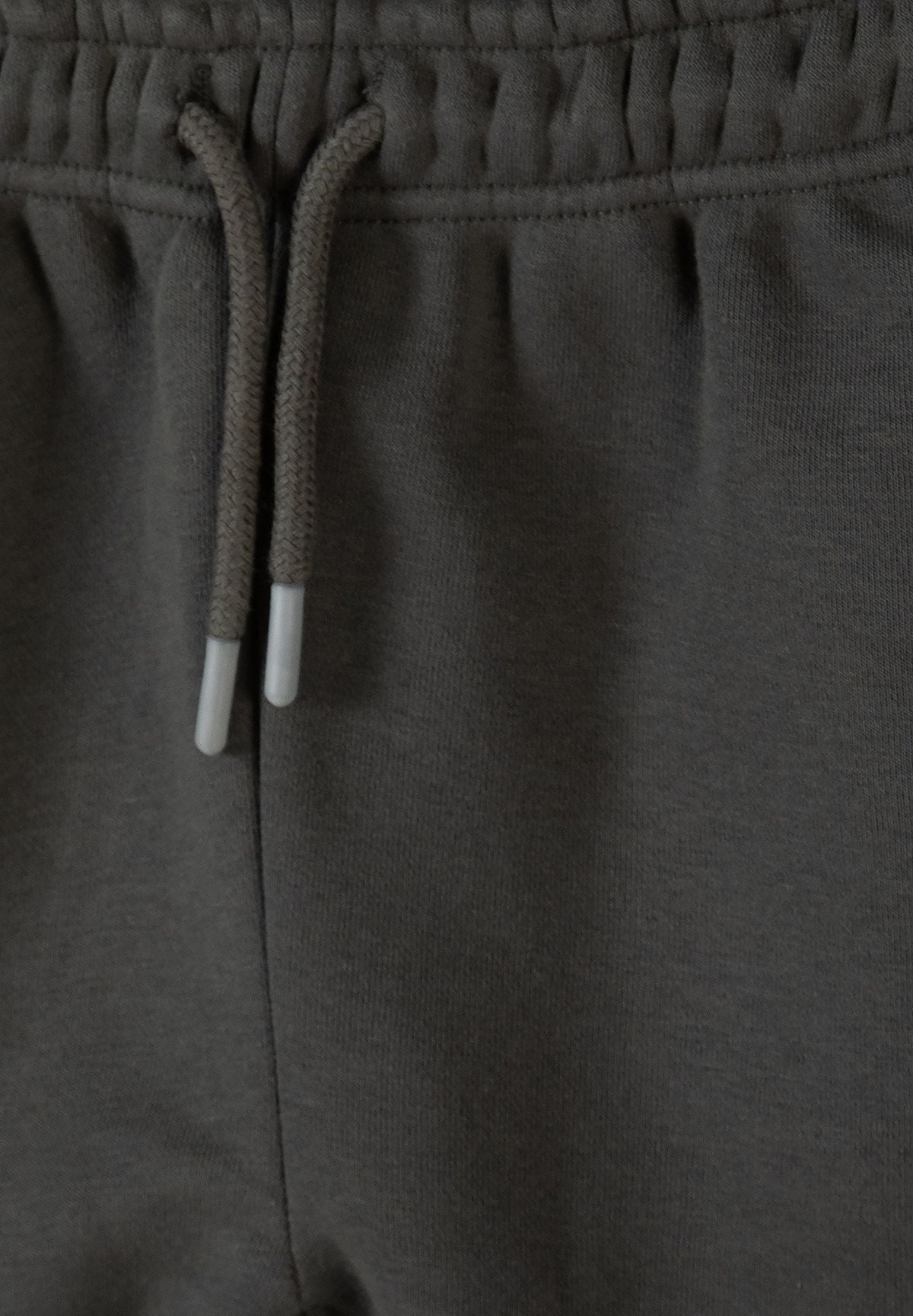 Close-up of khaki joggers' gathered waist and pale-tipped matching cord.