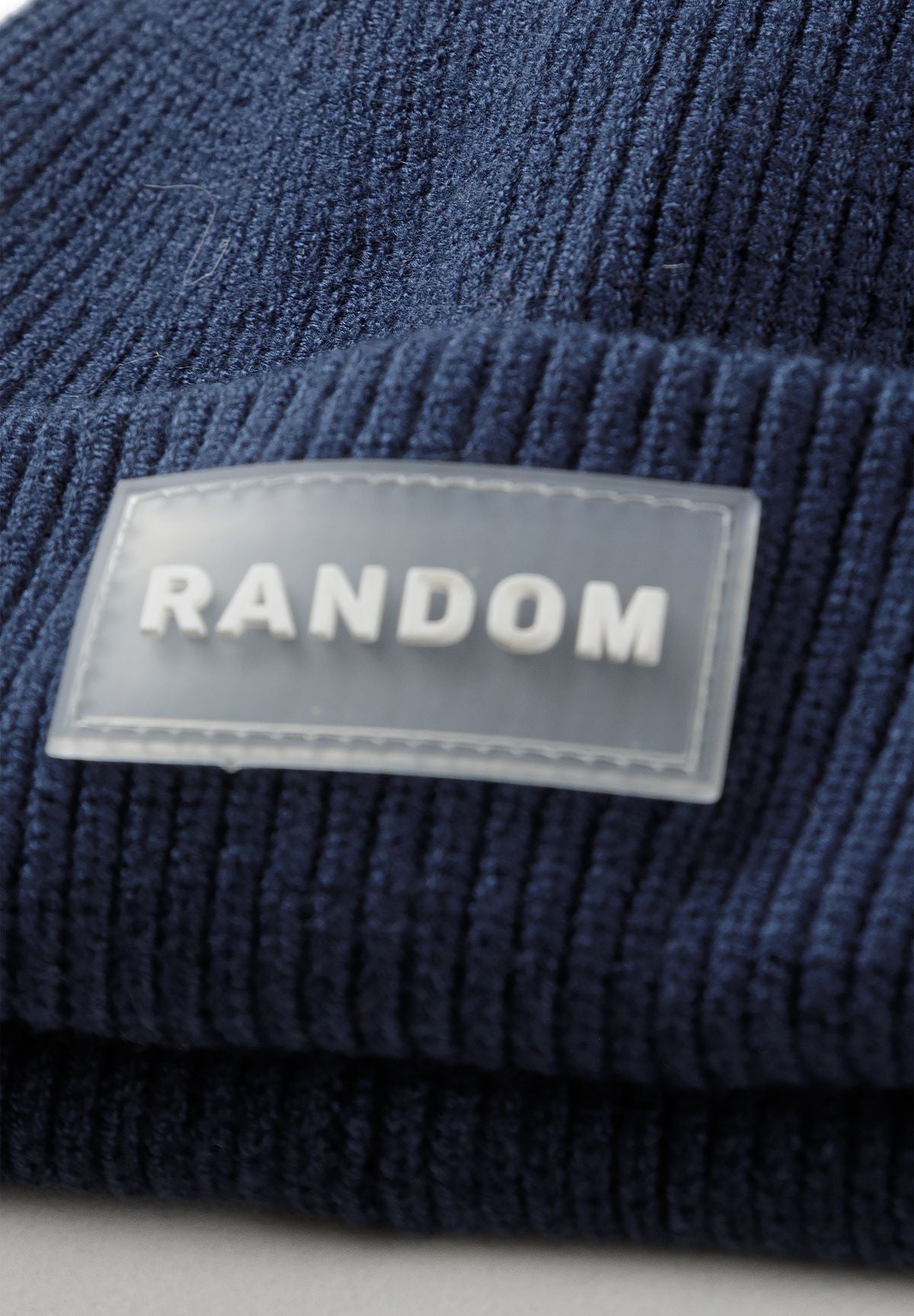 Bonnets à revers noirs et bleu marine pour garçons (lot de 2), gros plan sur l'écusson « Random ».