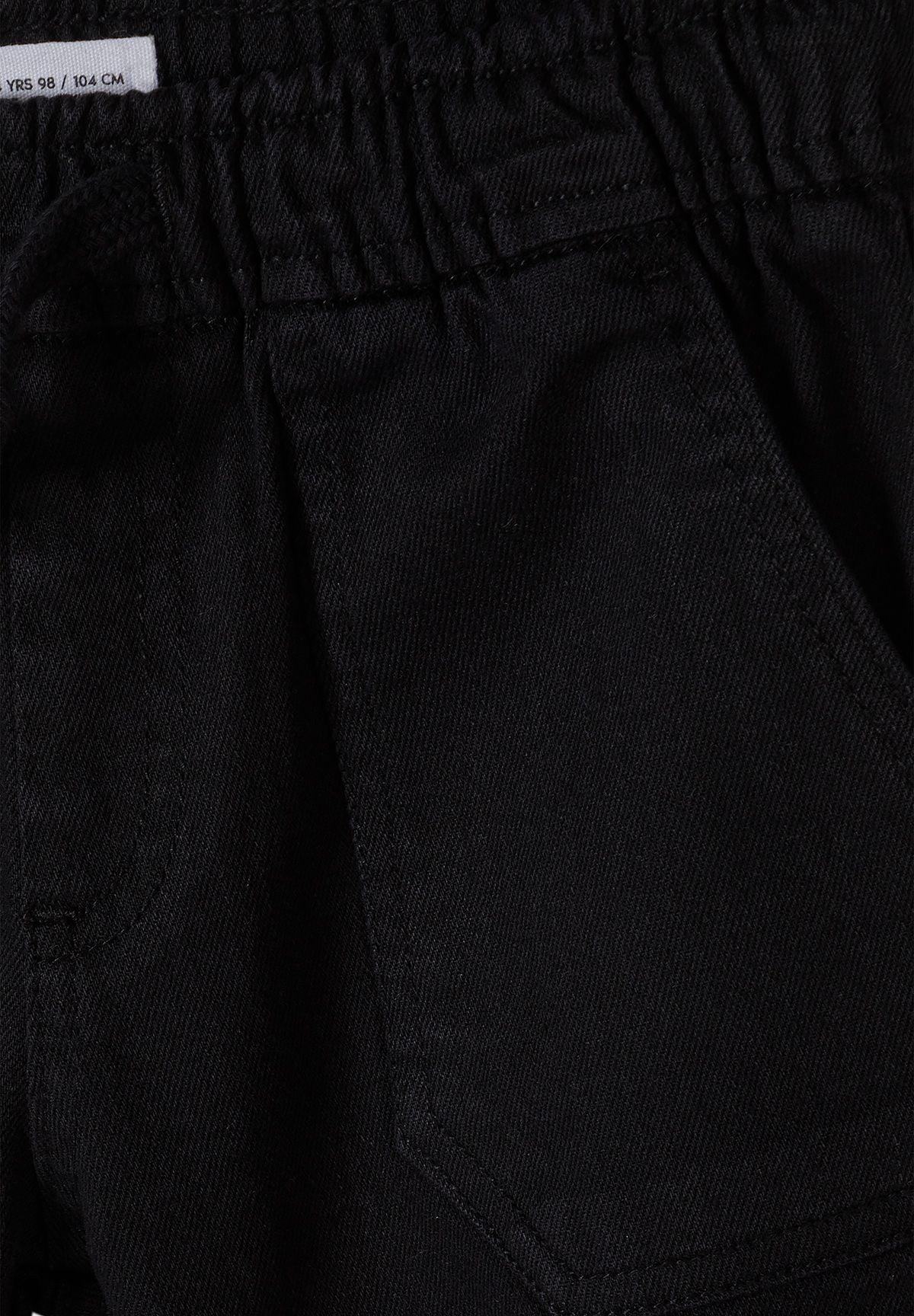 Zwarte broek met omgeslagen pijpen voor jongens, detail van de tailleband en de zak.