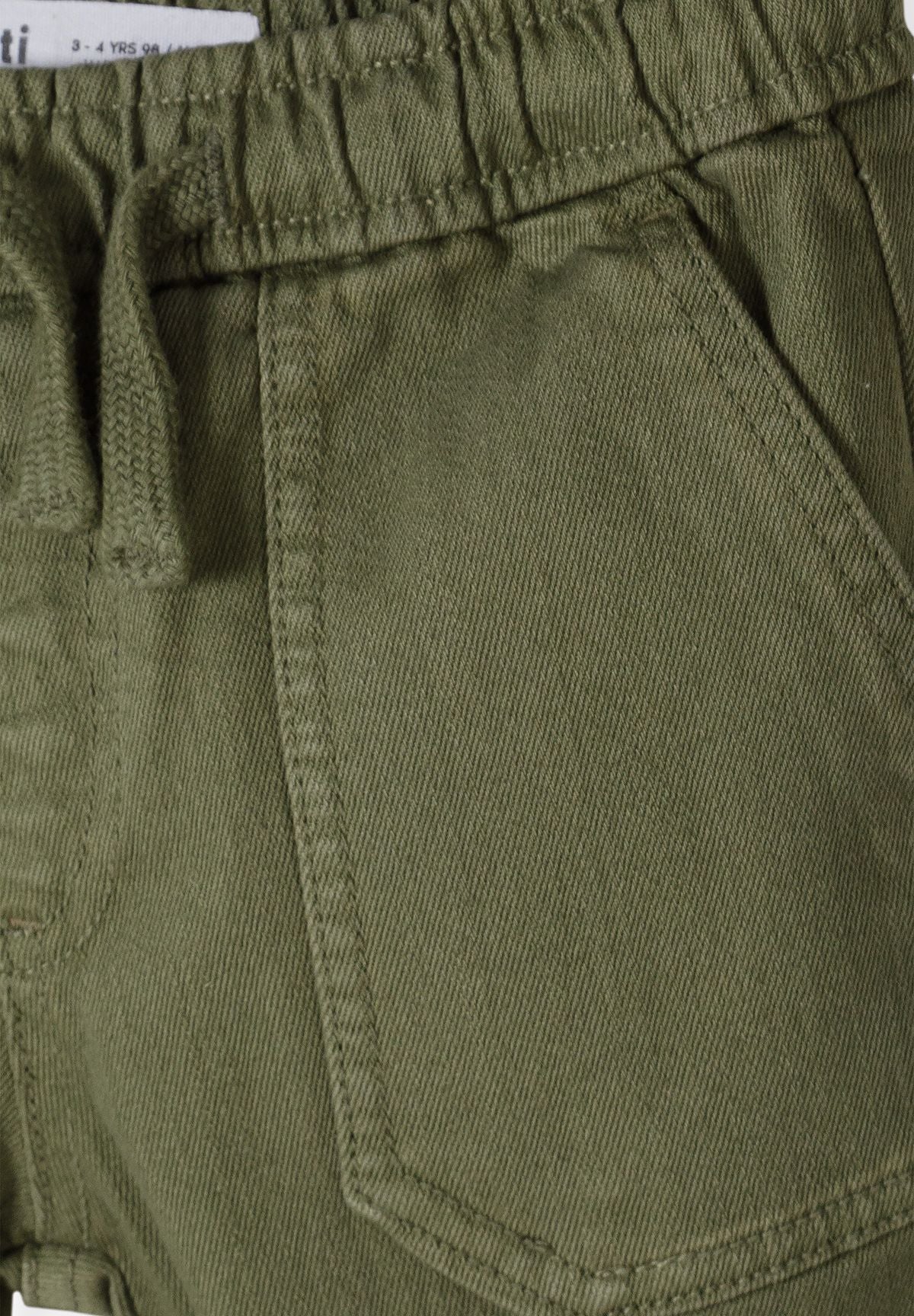 Close-up of olive trousers' elastic waist, drawcord and stitched front pocket.