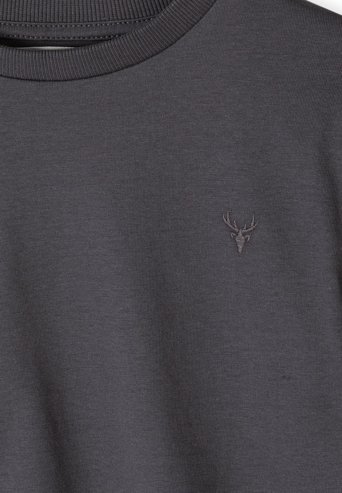 Close-up of tonal stag-head embroidery on charcoal-grey top.